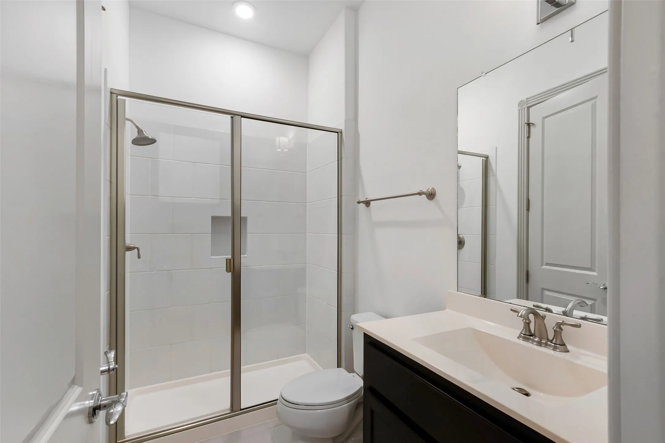 Contemporary bathroom featuring a frameless glass shower enclosure with subway tile surround and built-in niche