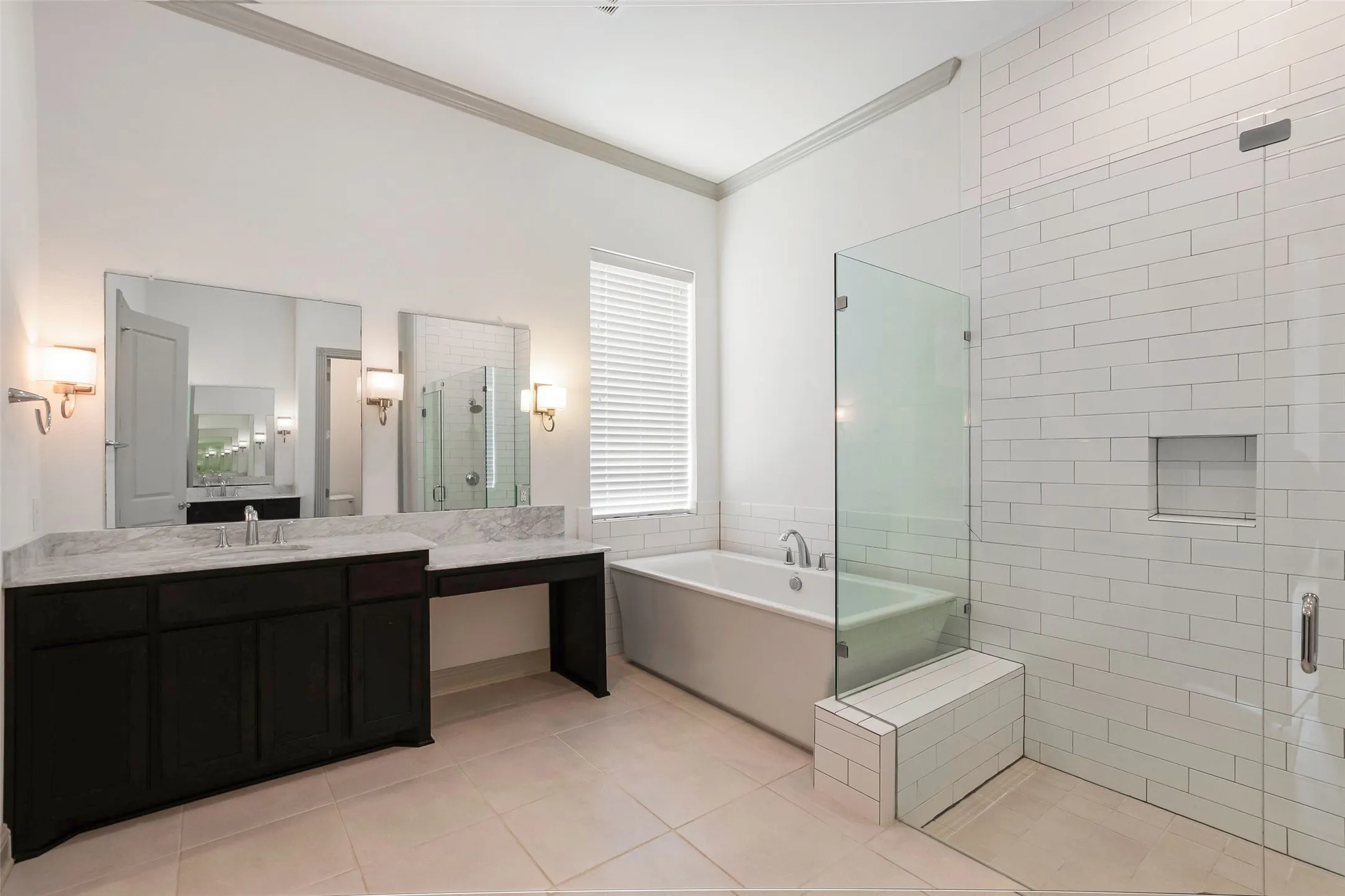 Spacious bathroom featuring a dual vanity with a light-toned countertop, a built-in soaking tub, a separate glass-enclosed shower with white subway tile, and light-toned tile flooring