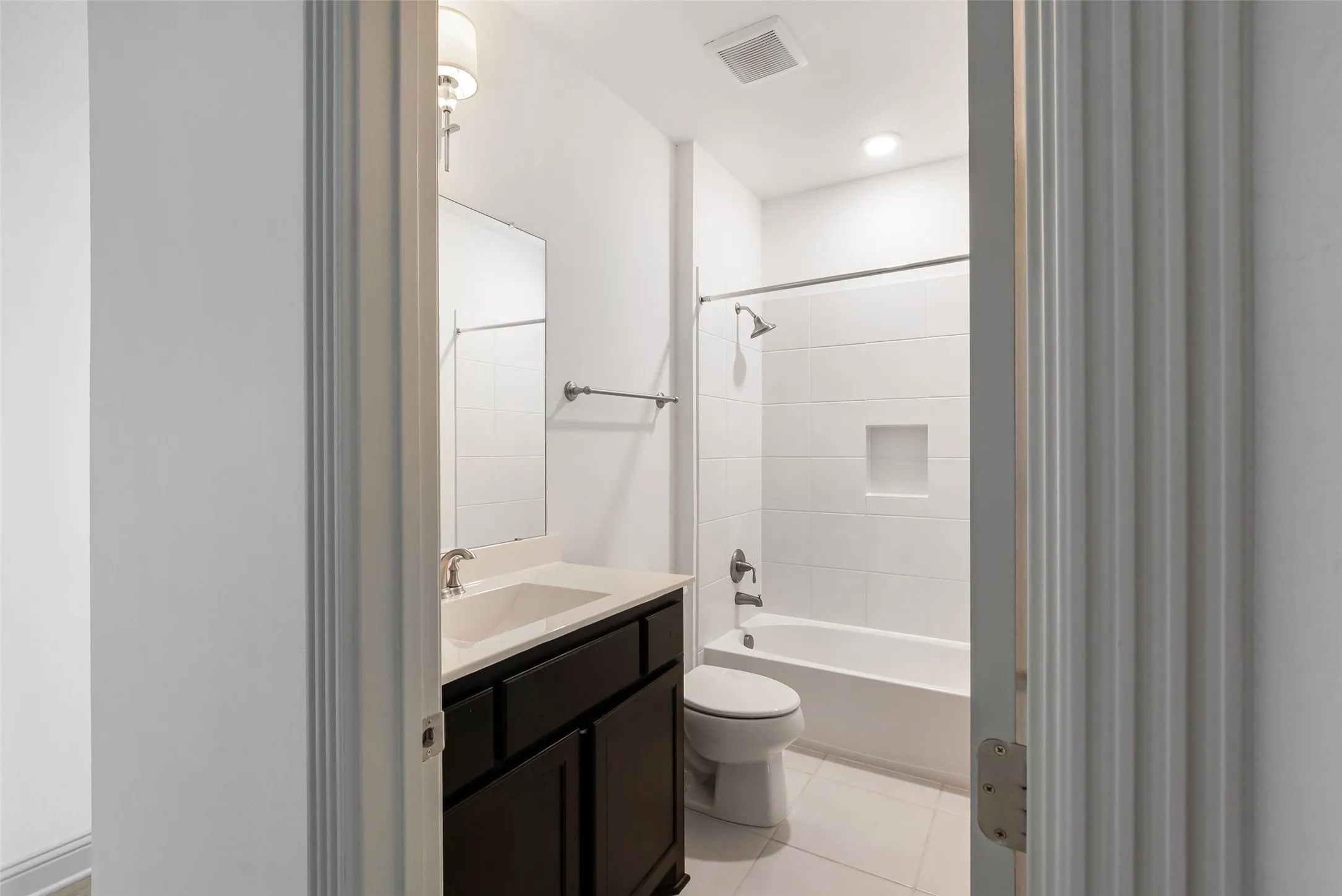 Bathroom featuring a dark wood-finish vanity with a light countertop, an undermount sink, and a framed mirror