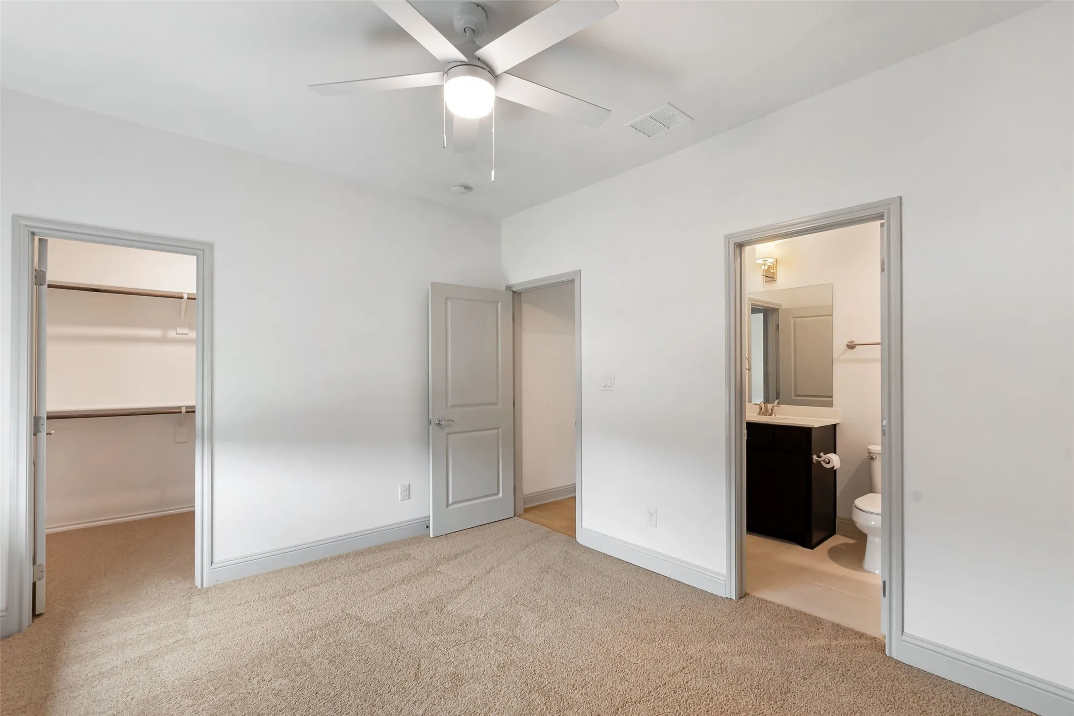 Recent updated carpeted interior room featuring a ceiling fan with integrated lighting, a built-in closet with shelving, and a separate bathroom entrance