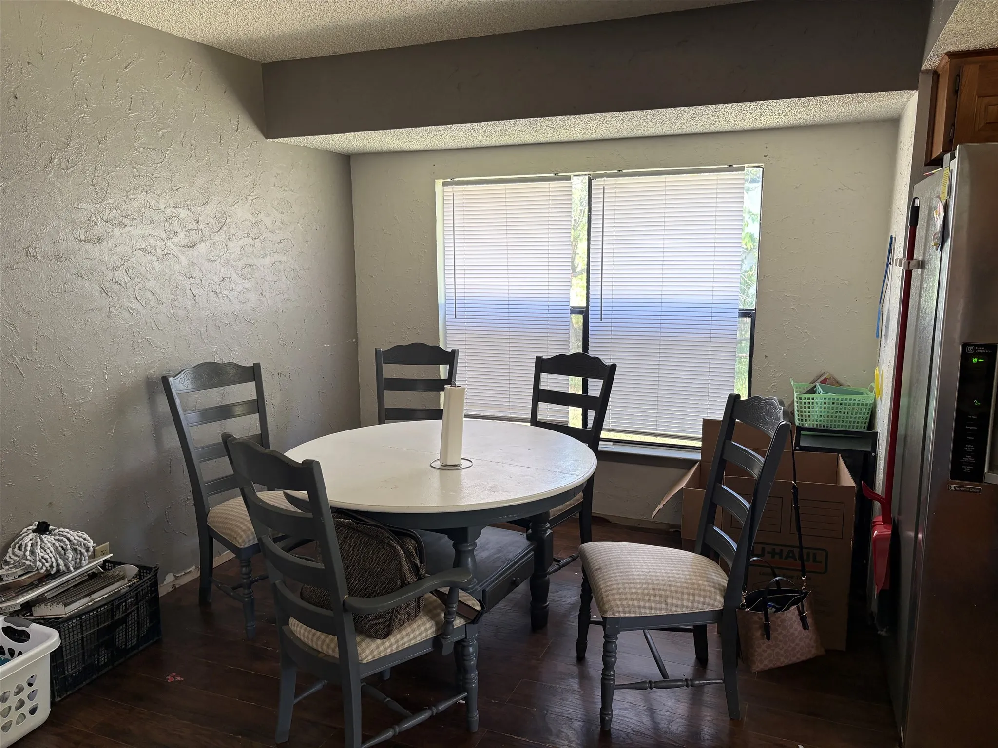 Dining area featuring wood-finish flooring, textured wall finishes, and a double window with horizontal blinds