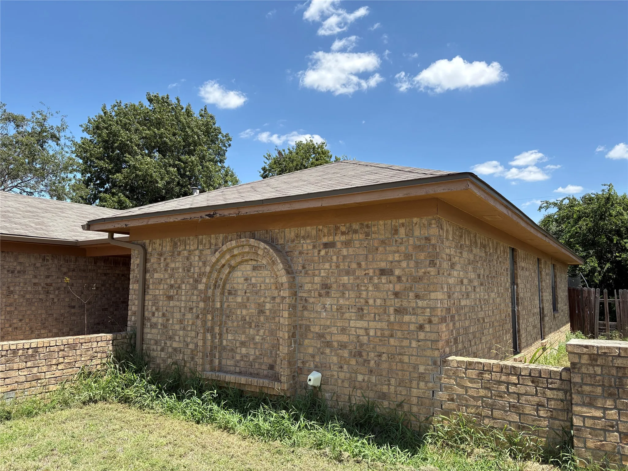 Brick exterior with an arched brick inlay feature, brown eaves, and a shingled roof