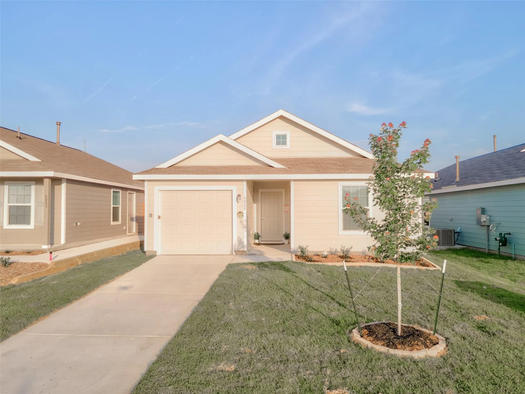 Single-story residence featuring light-colored siding, an attached garage, and a concrete driveway