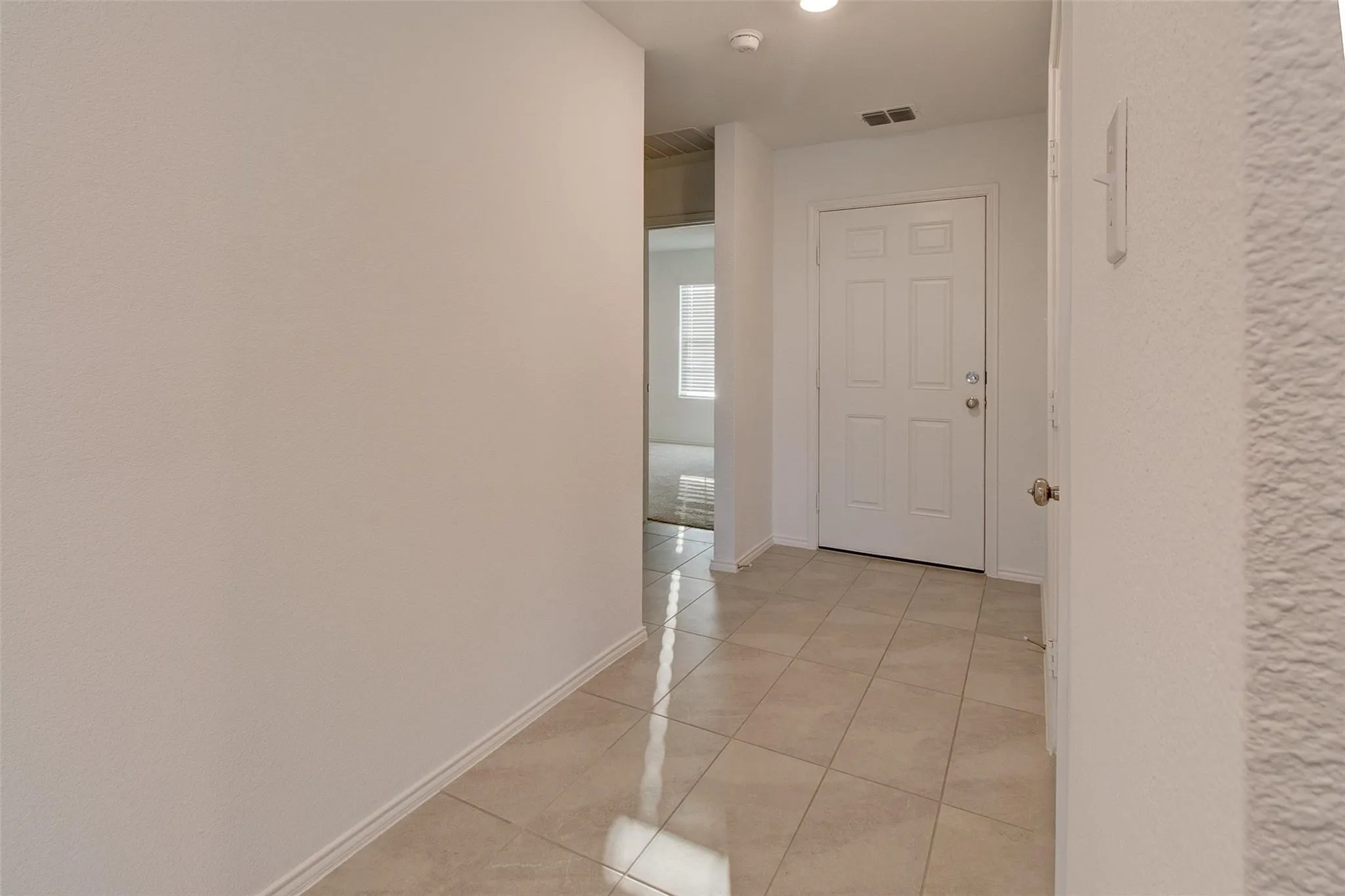 Entryway featuring light-toned square tile flooring, a white paneled door, and neutral wall finishes