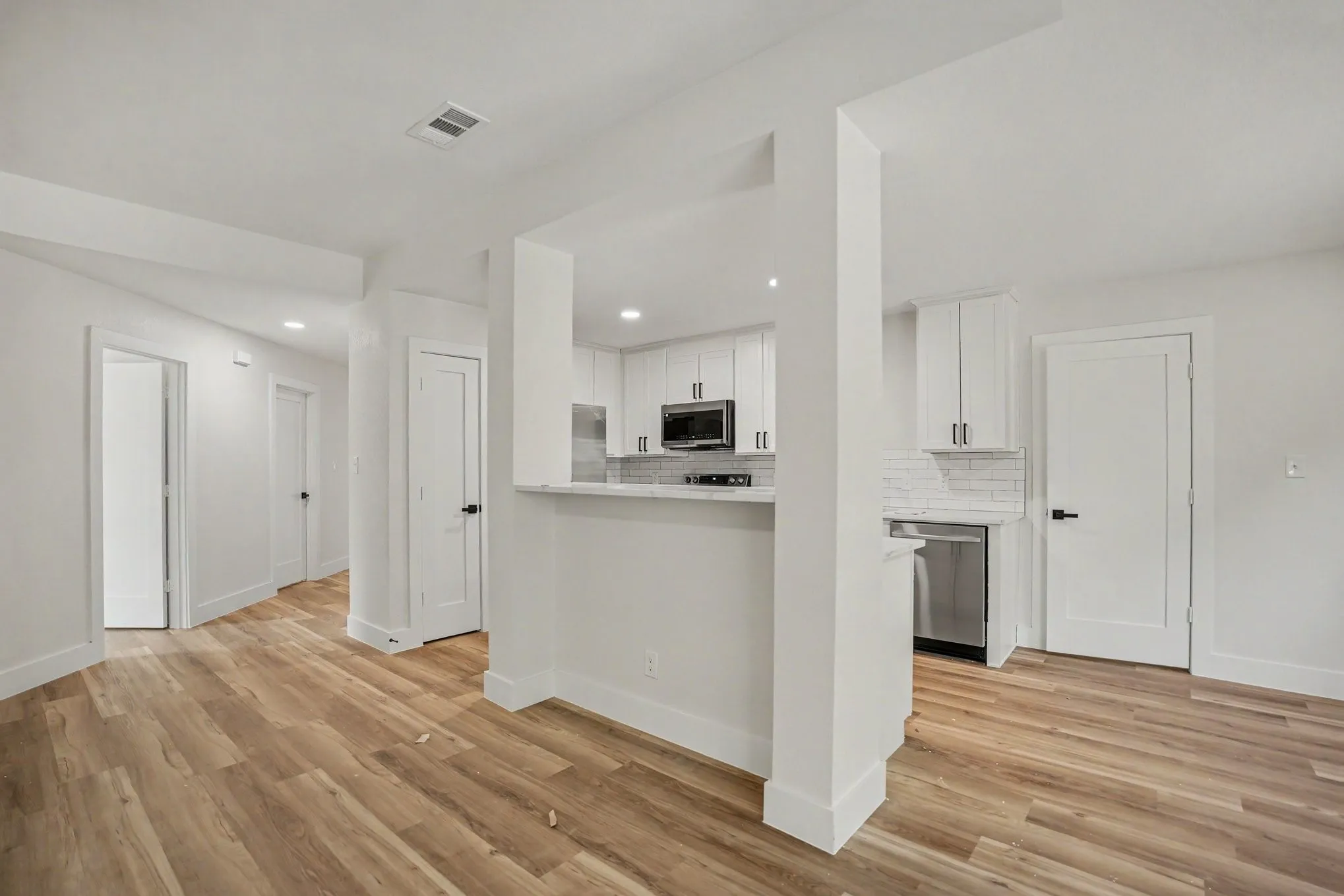 Kitchen area featuring white shaker cabinetry, stainless steel appliances, a subway tile backsplash, and a breakfast bar