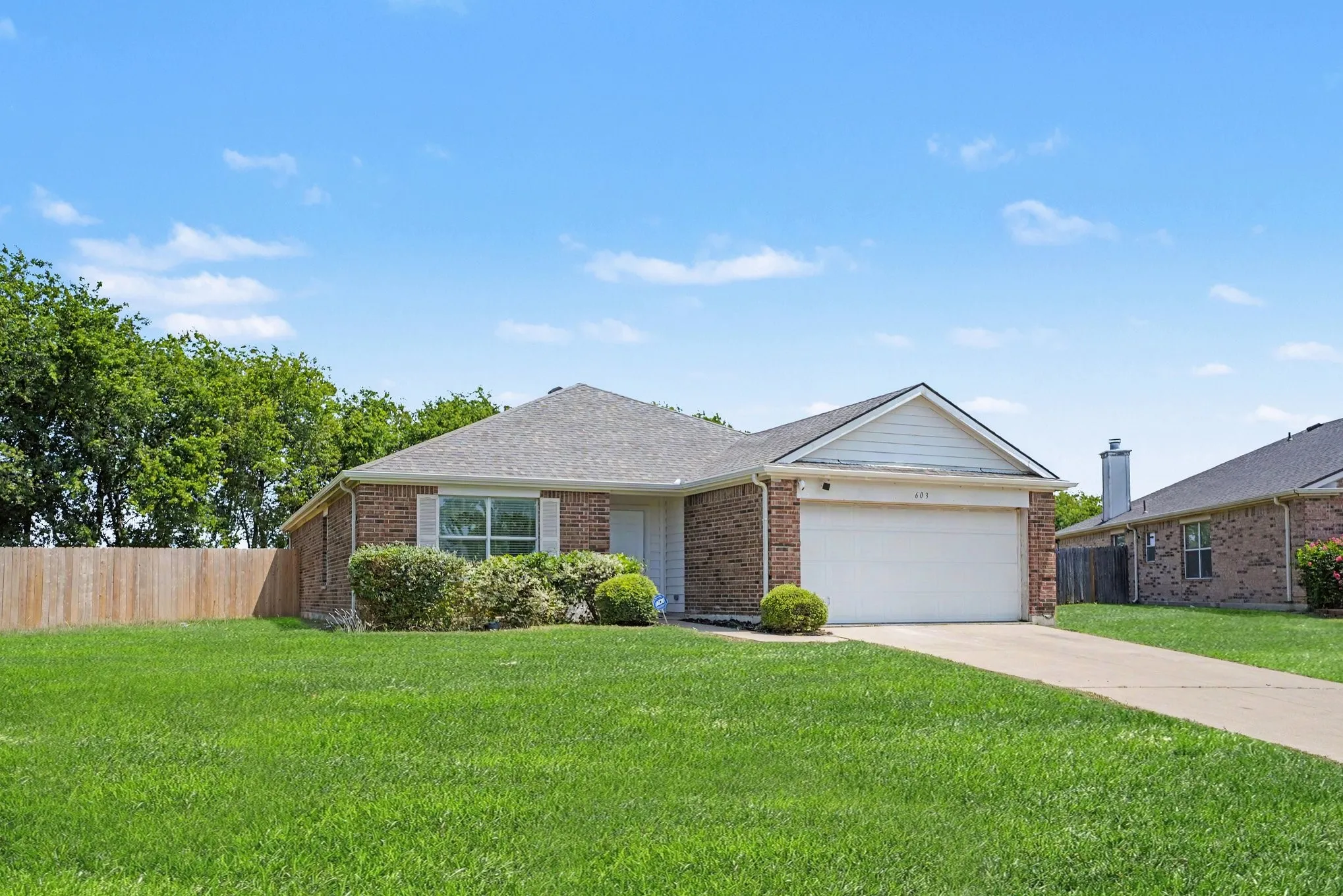 Charming brick ranch home featuring a spacious two-car attached garage, manicured lawn, and mature landscaping