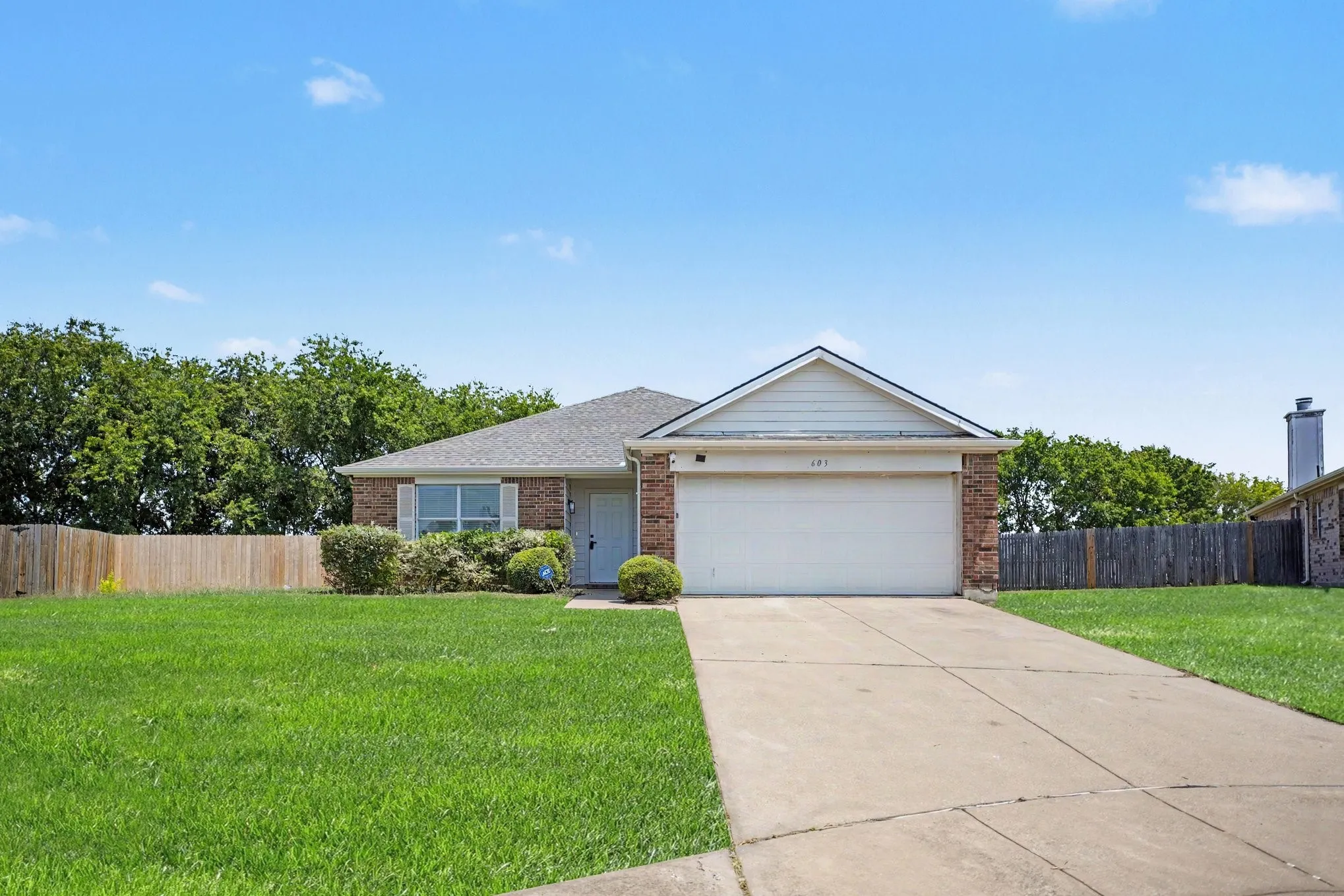 Charming one-story brick residence featuring a welcoming front elevation with peaked roofline, blue entry door, and two-car garage