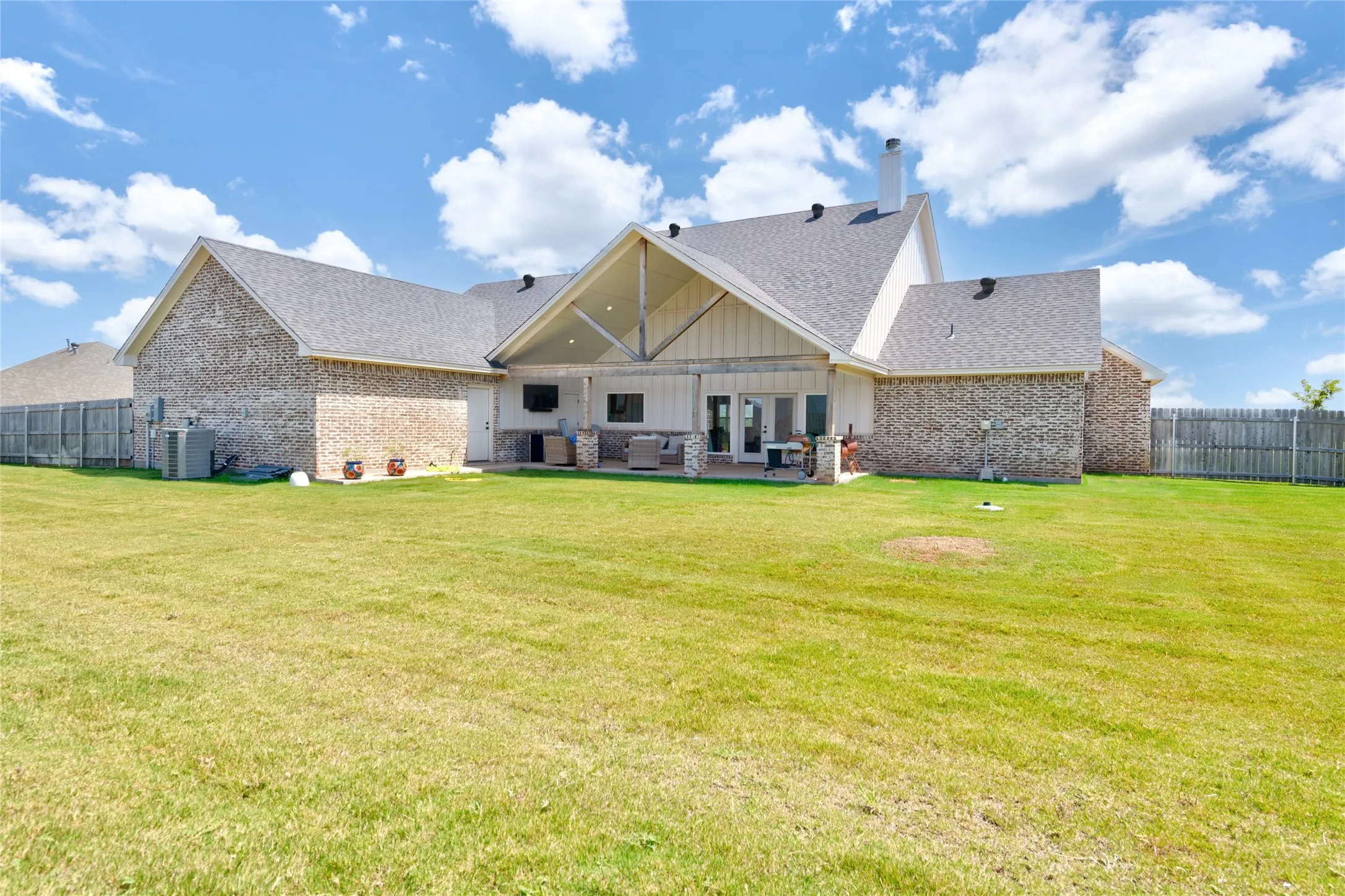 Expansive rear exterior featuring a covered patio with an exposed beam vaulted ceiling