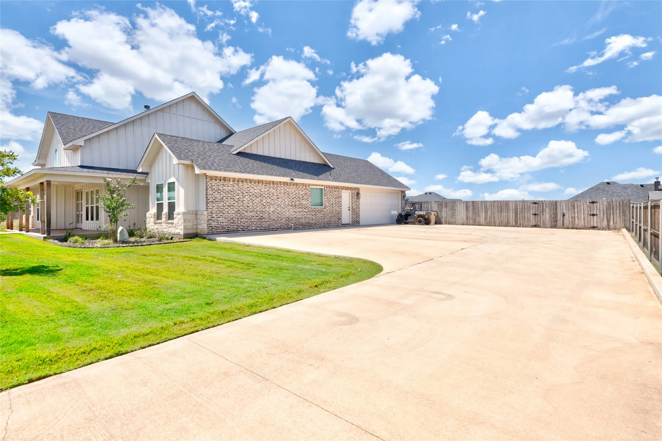 Spacious concrete driveway accommodating multiple vehicles, bordered by a green lawn