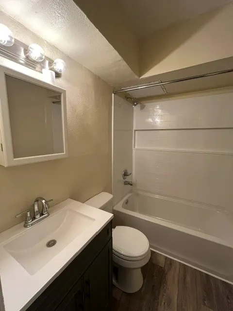 Bathroom featuring a dark wood-finish vanity with an integrated sink, chrome faucet, and a standard white bathtub with a shower