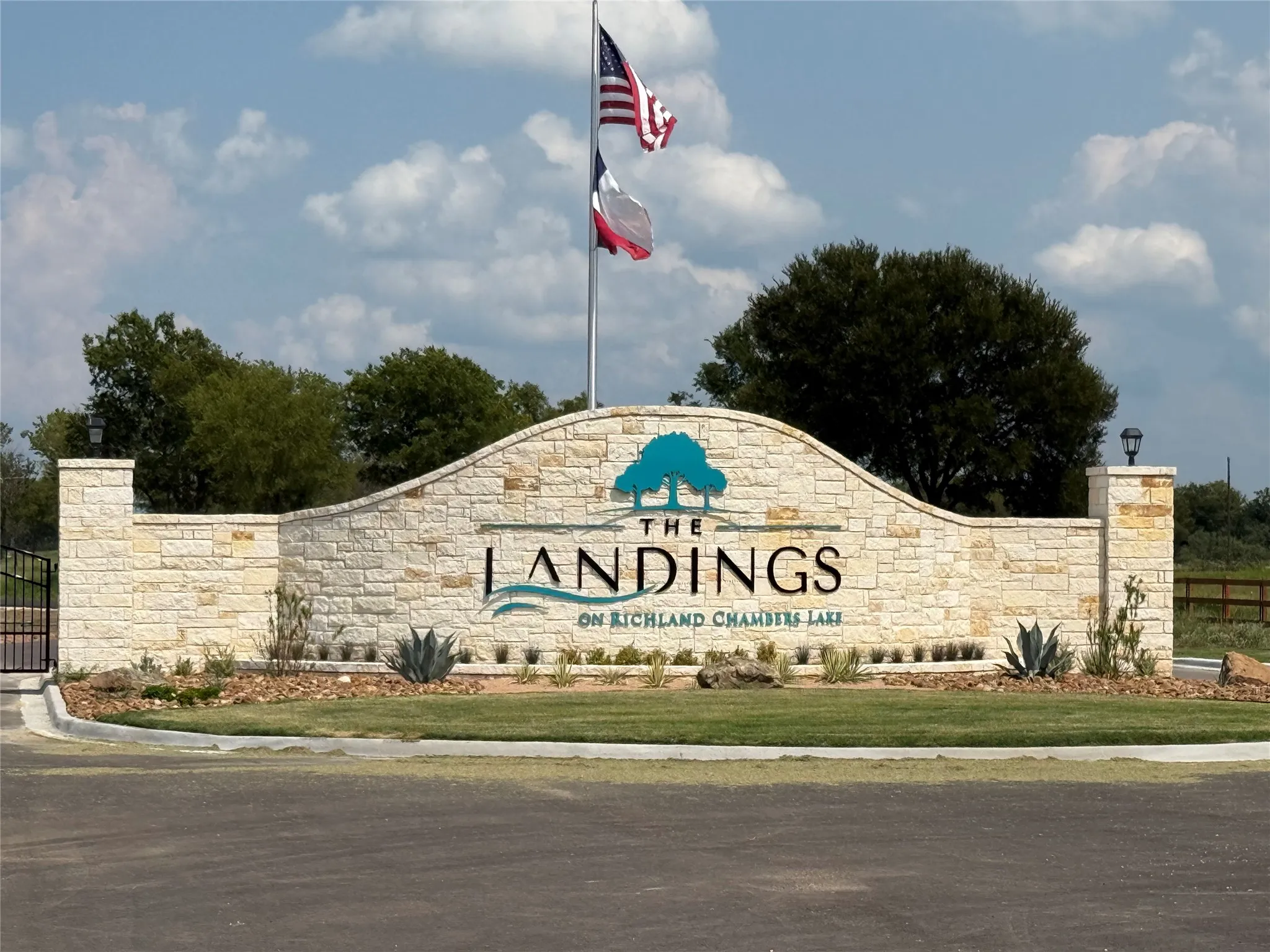 Stonework entry signage featuring "The Landings on Richland Chambers Lake" with integrated landscaping