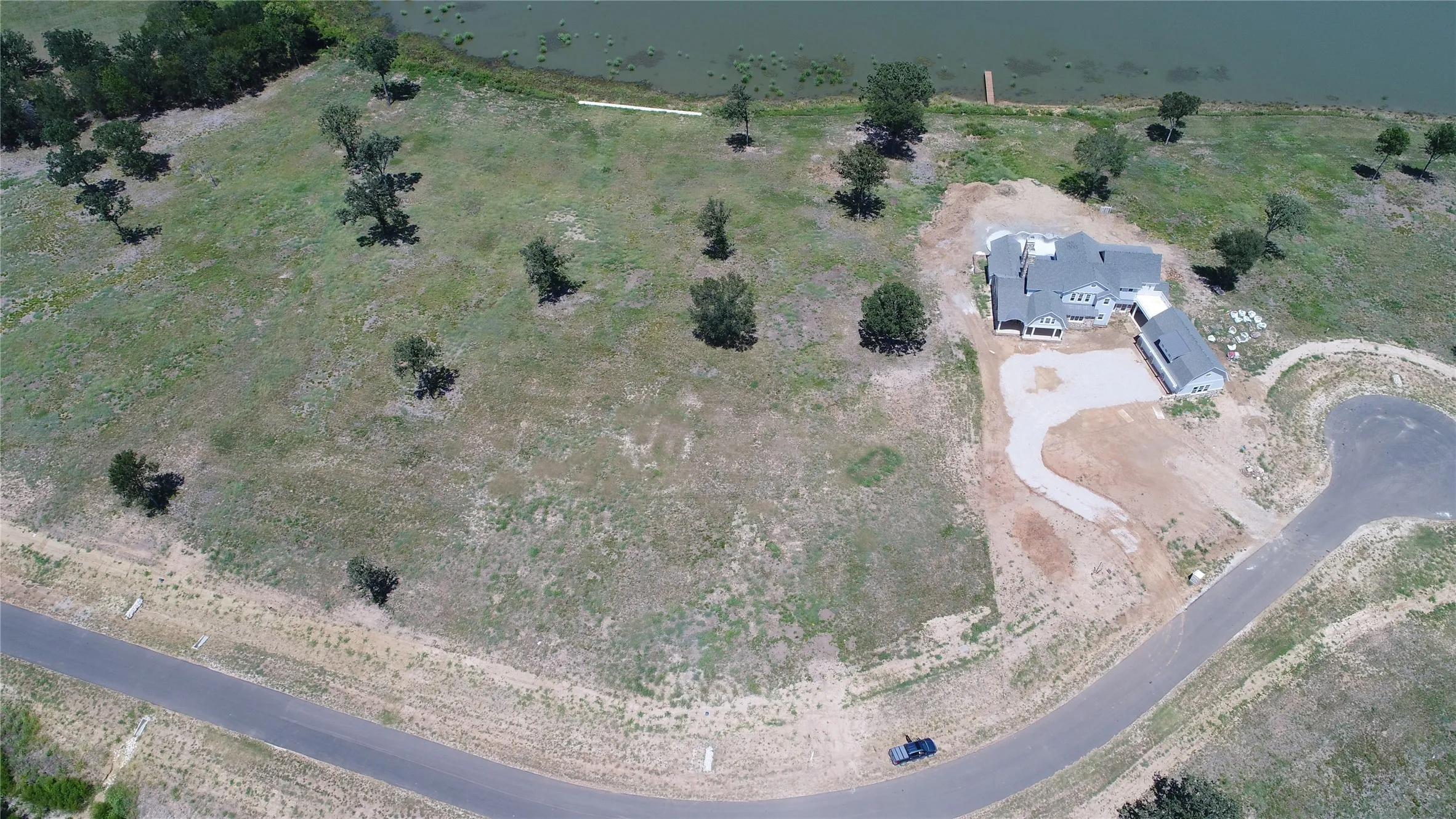 Expansive lot with a newly constructed residence featuring a gray exterior and multiple gables