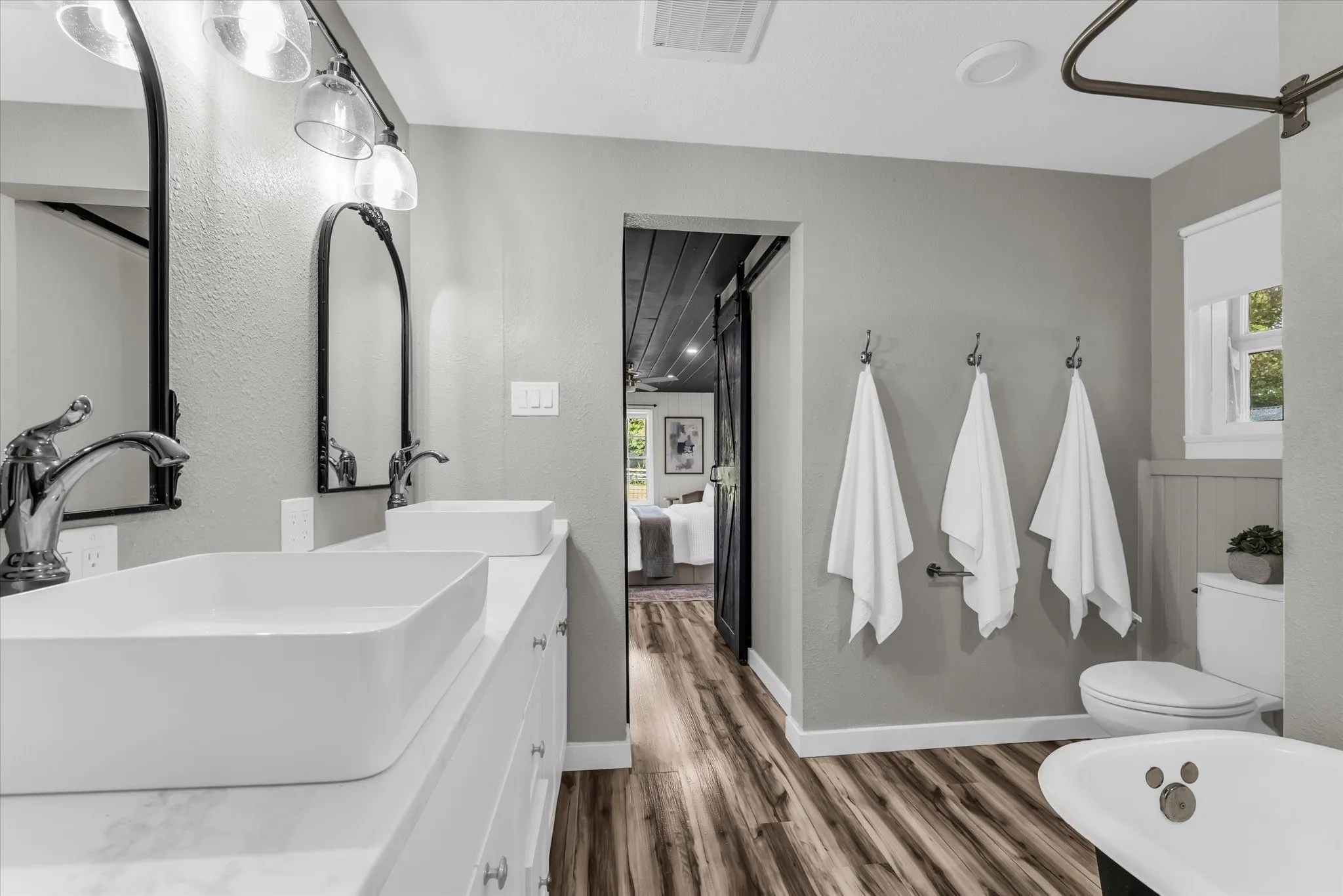 Bathroom featuring a dual vanity with rectangular vessel sinks, chrome faucets, and arched mirrors