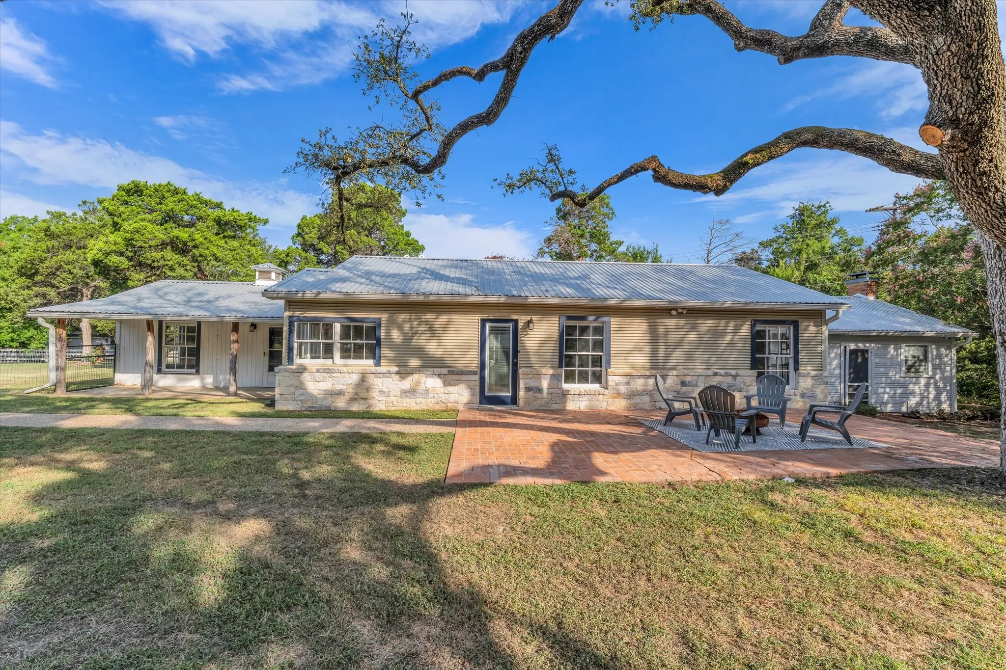 Exterior featuring a corrugated metal roof, stone and stucco siding, and multiple windows with dark trim