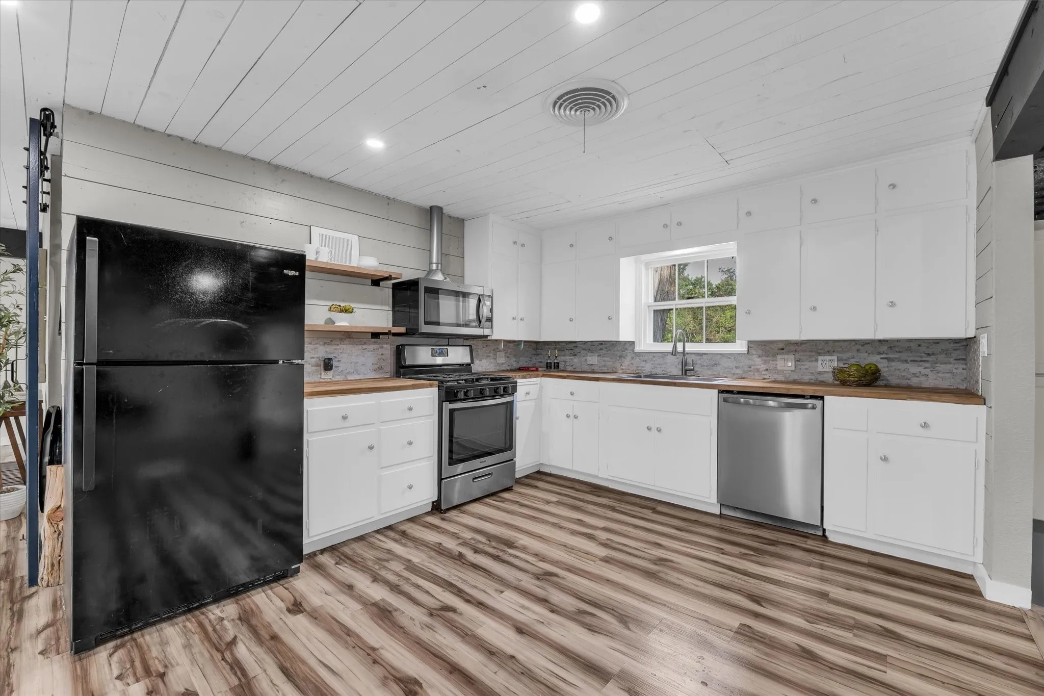 Kitchen featuring white cabinetry, wood-finish countertops, stainless steel appliances, and wood-finish flooring