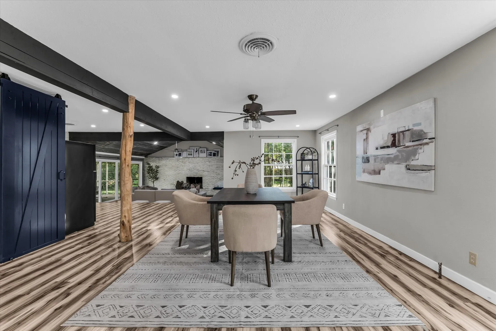 Spacious room featuring wood-finish flooring, a dark ceiling fan, recessed lighting, and a dark barn door