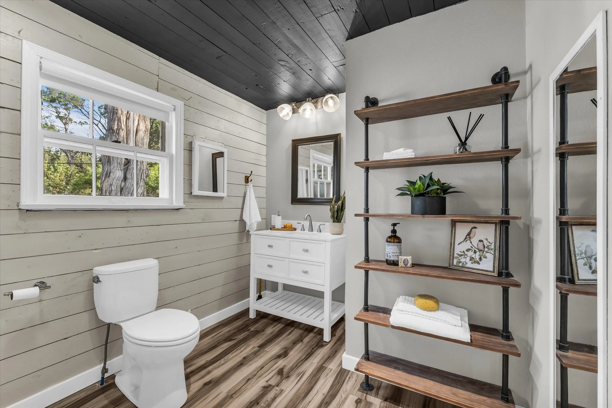 Bathroom featuring a white vanity with a rectangular sink, a wall-mounted mirror, and a three-light fixture