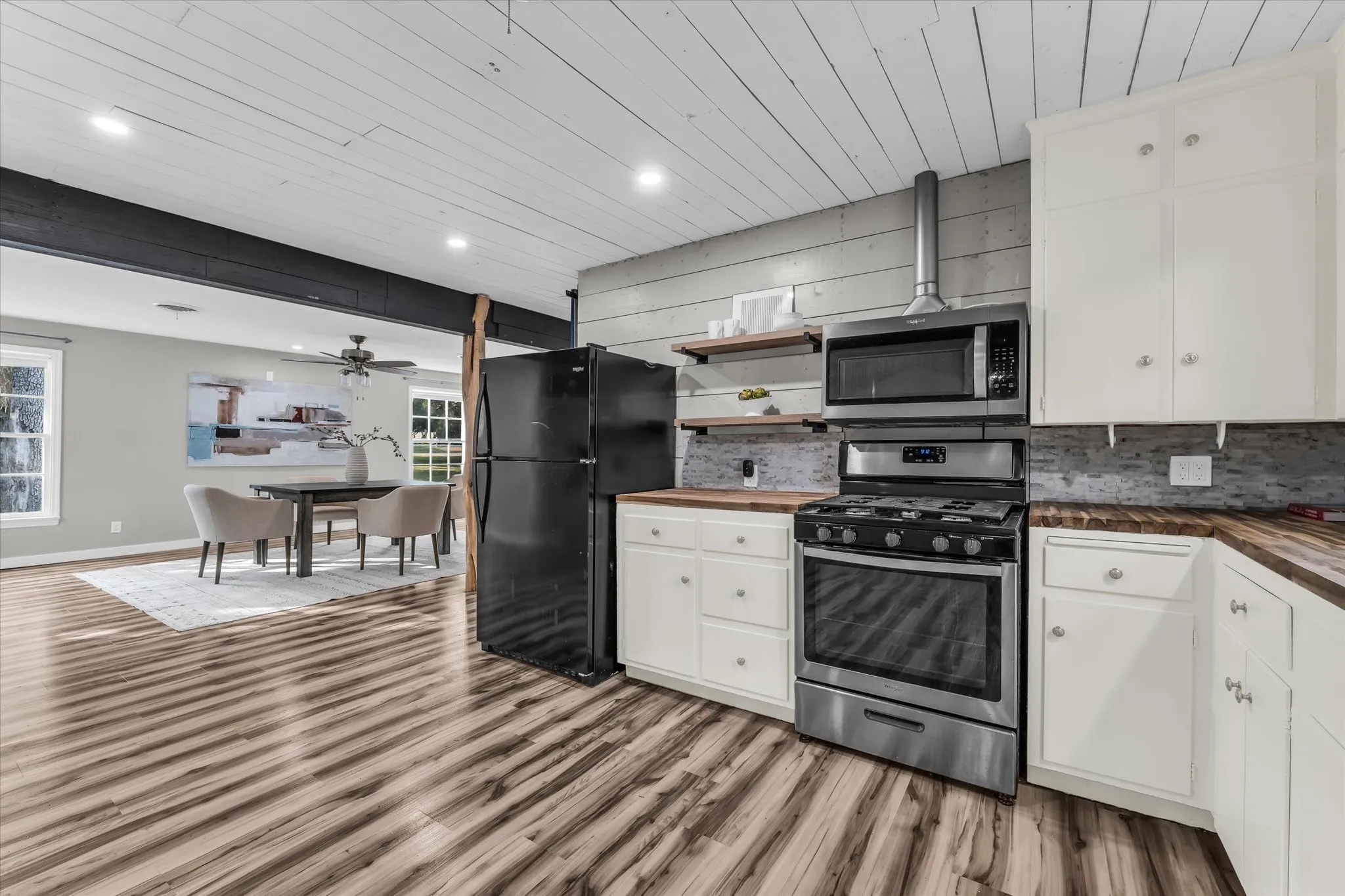 Kitchen featuring white cabinetry, wood-finish countertops, stainless steel appliances, and a grey tile backsplash