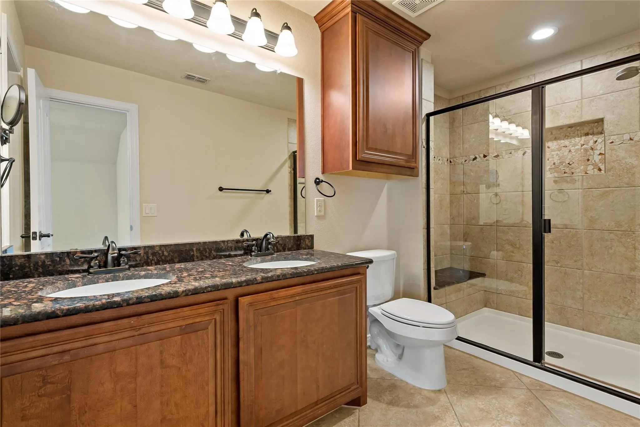 Bathroom featuring a dual vanity with a dark granite countertop, undermount sinks, and oil-rubbed bronze fixtures