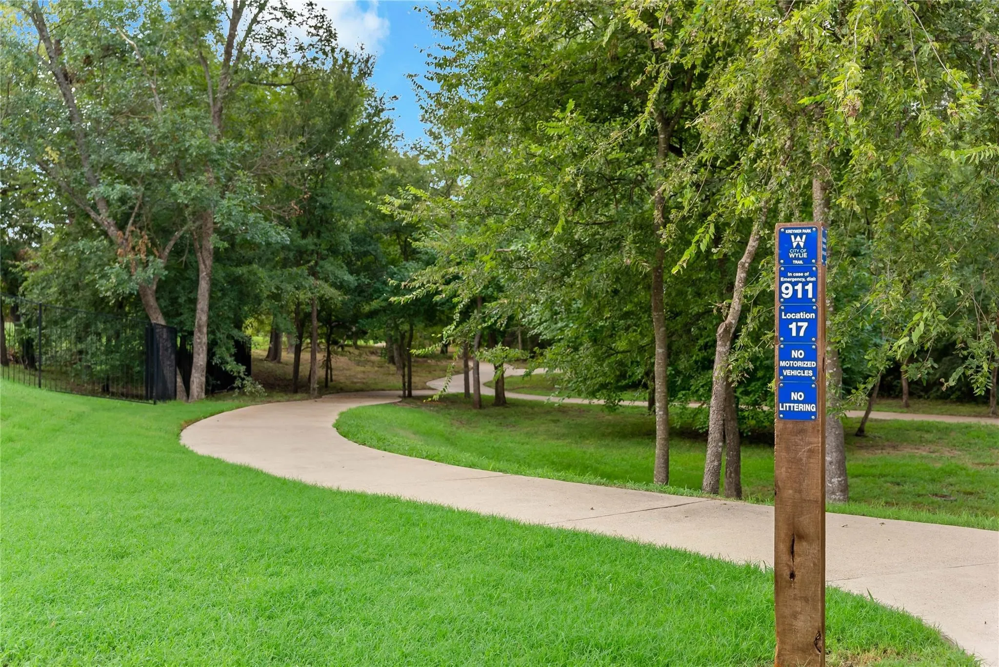 Paved walking path bordered by lush green lawns and mature trees