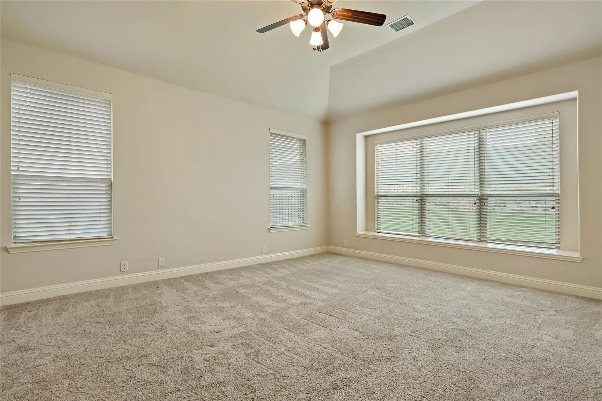 Carpeted room with a vaulted ceiling and a ceiling fan