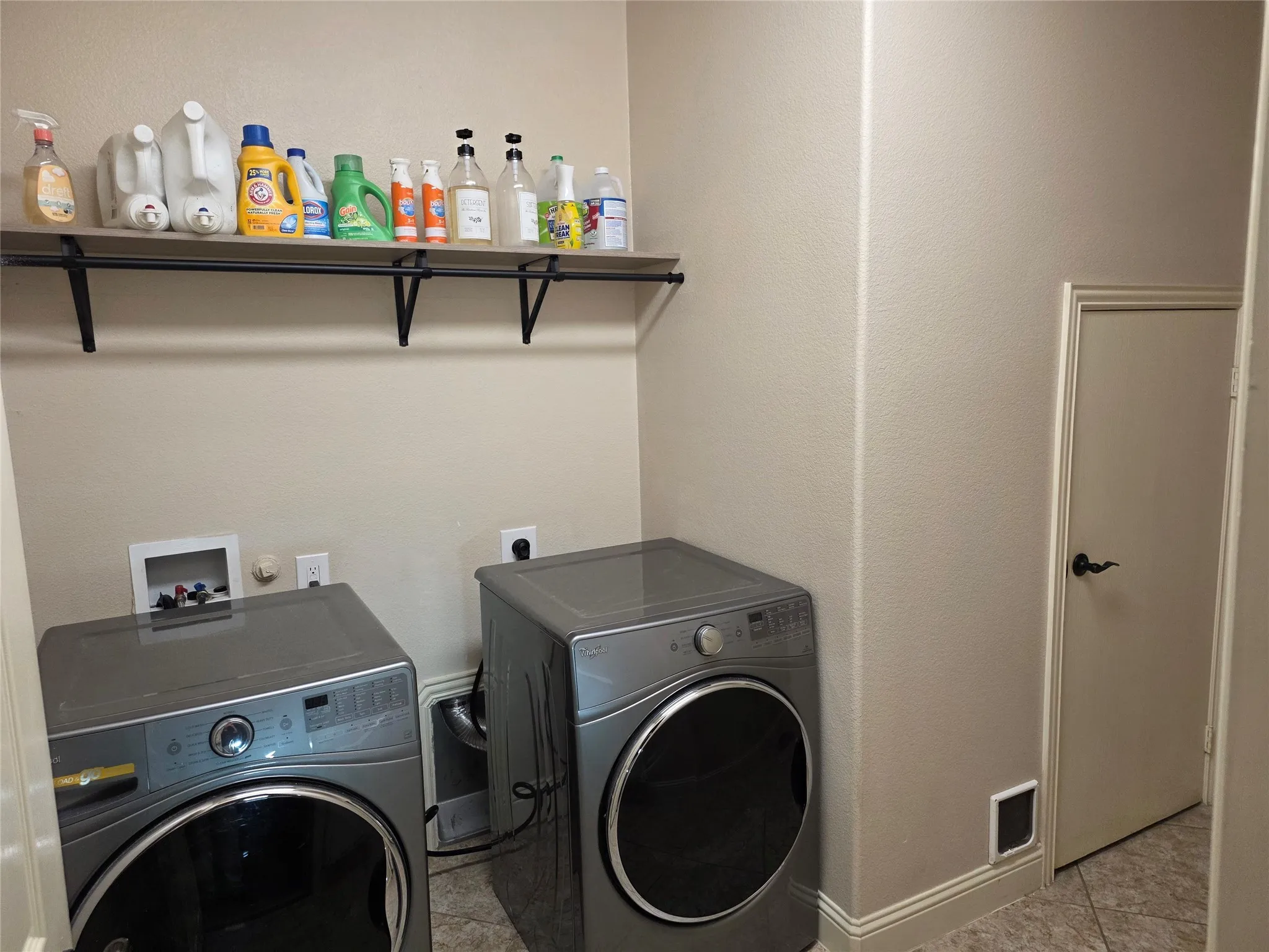 Dedicated laundry area featuring a wall-mounted shelf, utility hookups for appliances, and neutral wall tones