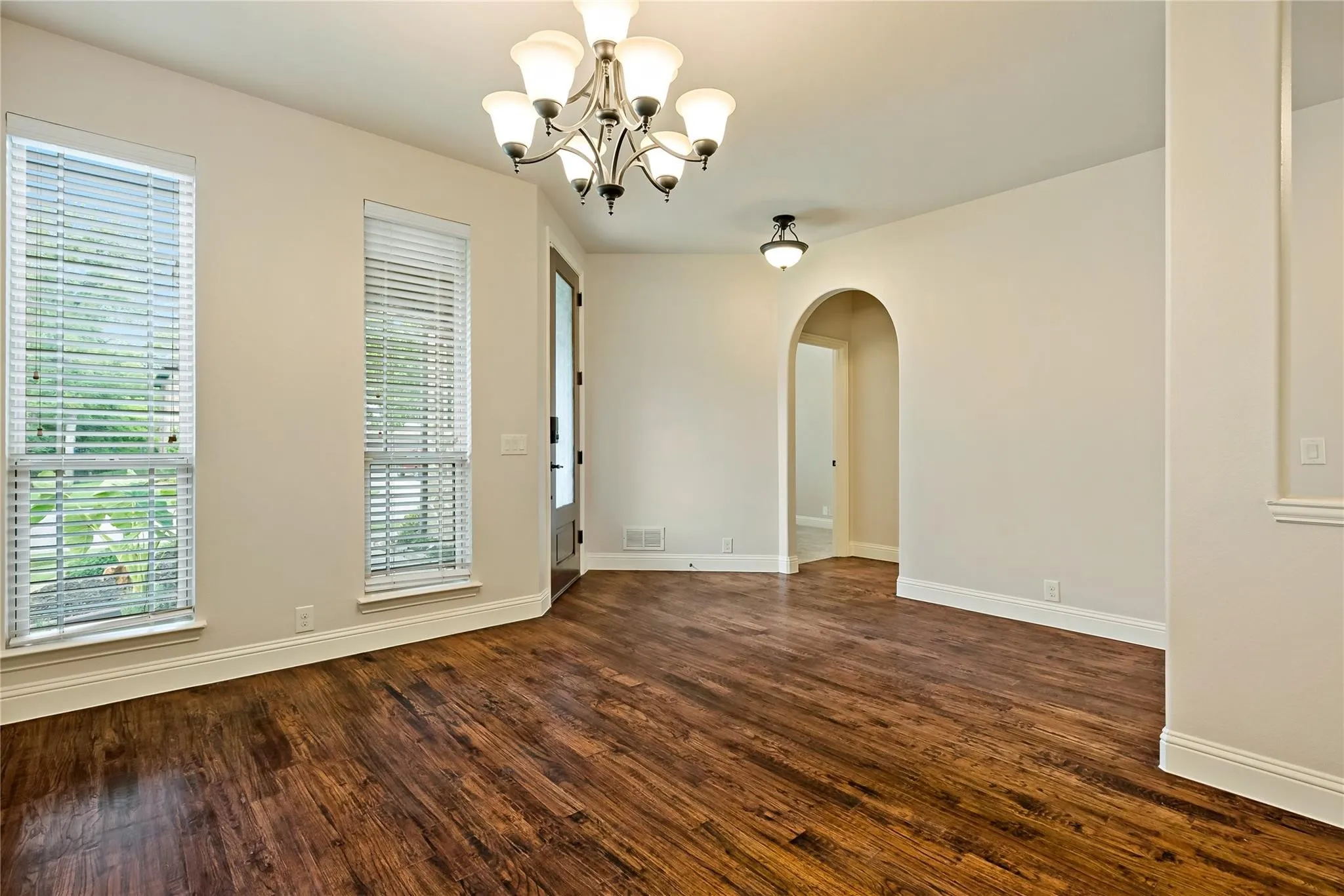 Spacious room featuring wood-finish flooring, neutral wall tones, and white baseboards