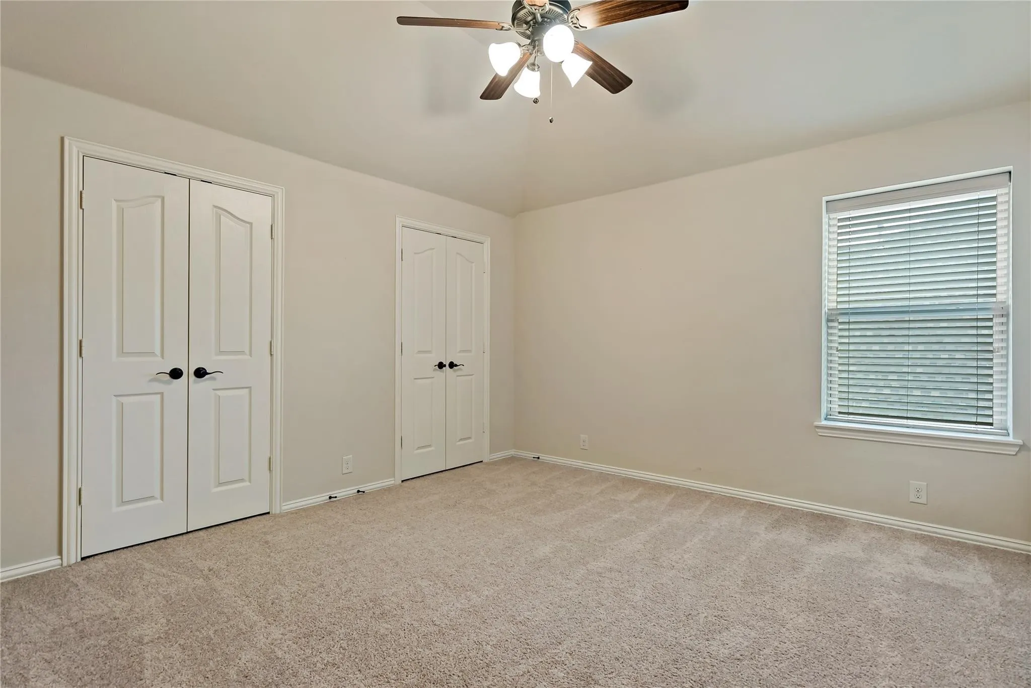 Carpeted room featuring a ceiling fan with light fixture, neutral wall paint, and white trim