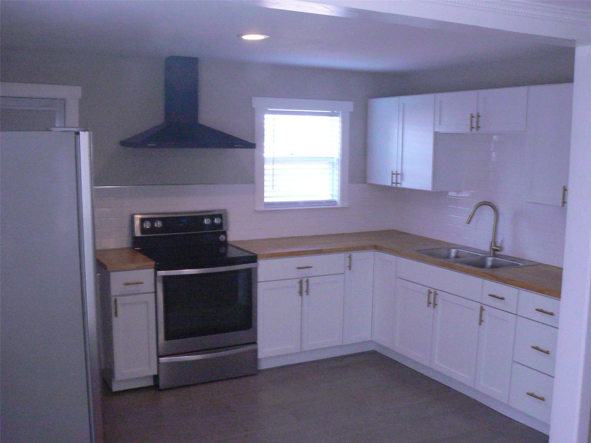 Updated kitchen with wood grain countertops. Smooth surface range. Side-by-side refrigerator. Venthood.