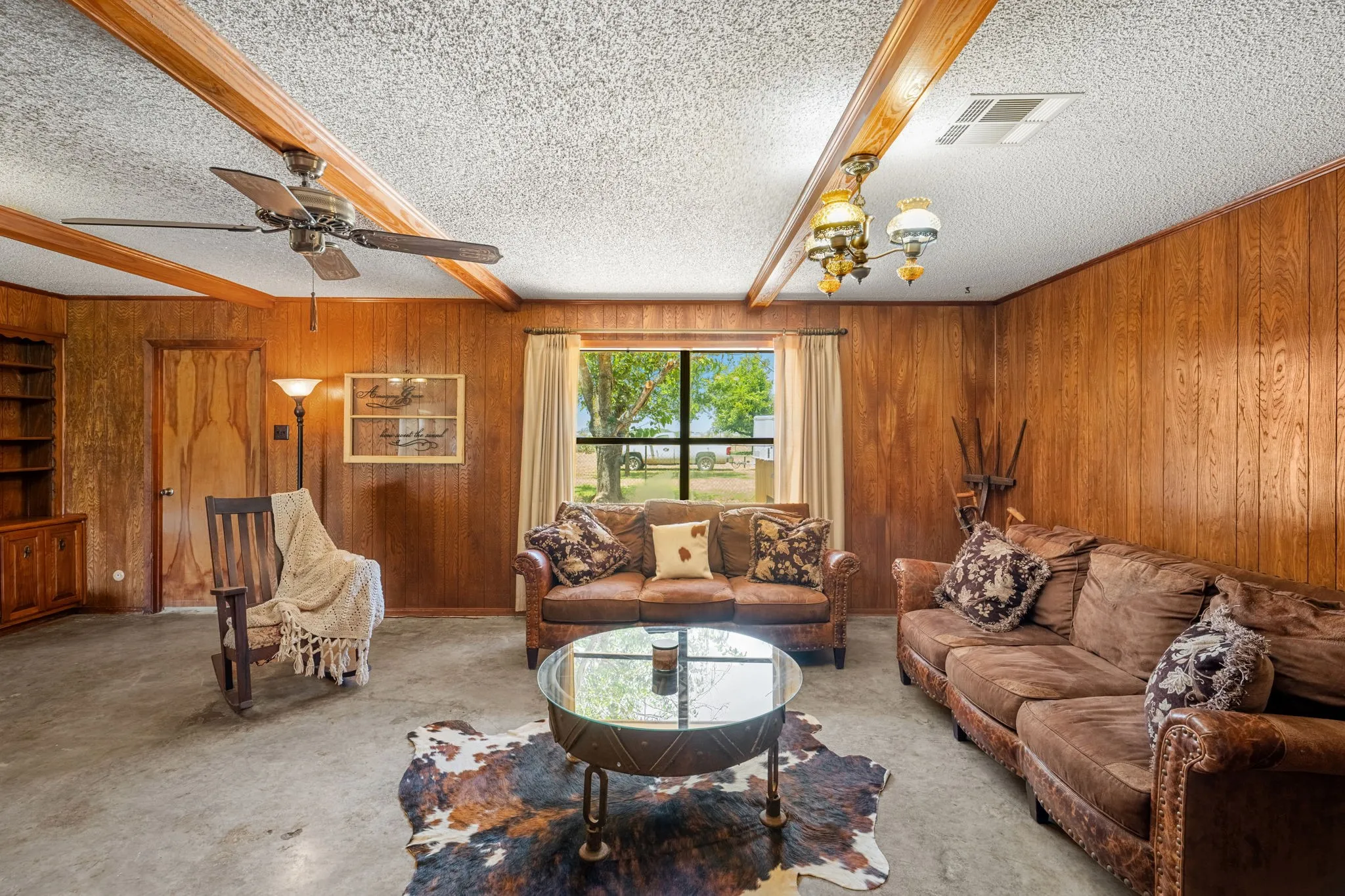 Living area featuring wood paneling, exposed ceiling beams, and concrete flooring