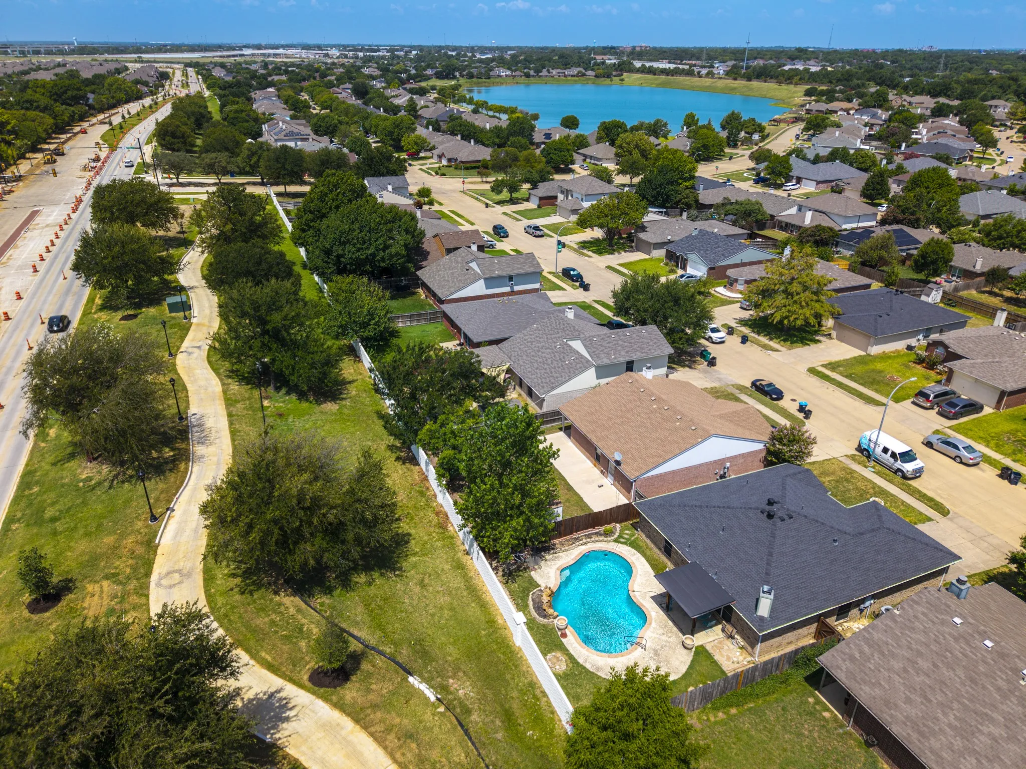 Residential property featuring a private swimming pool with stone surround, a dark-shingle roof, and a fenced backyard
