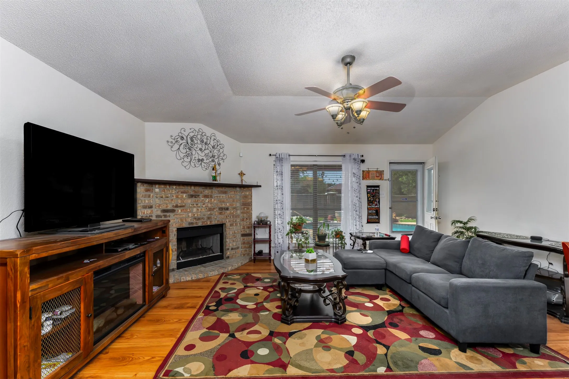 Living area featuring wood-finish flooring and a corner brick fireplace with a mantle
