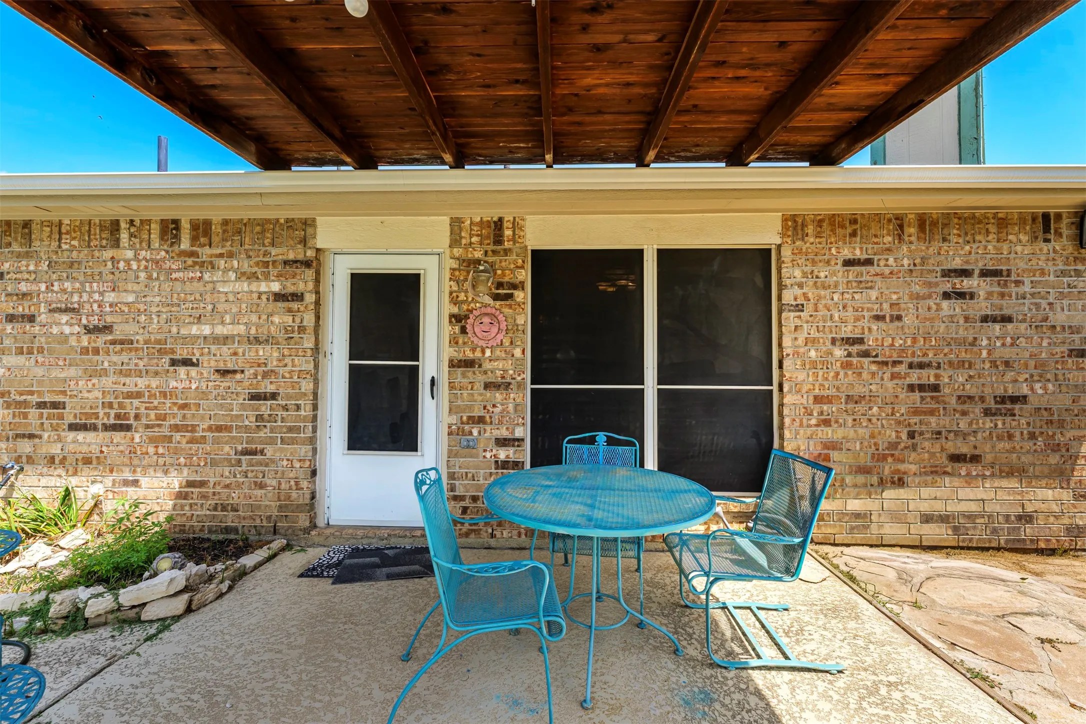 Covered patio featuring a wood-finish ceiling, brick exterior, and concrete flooring
