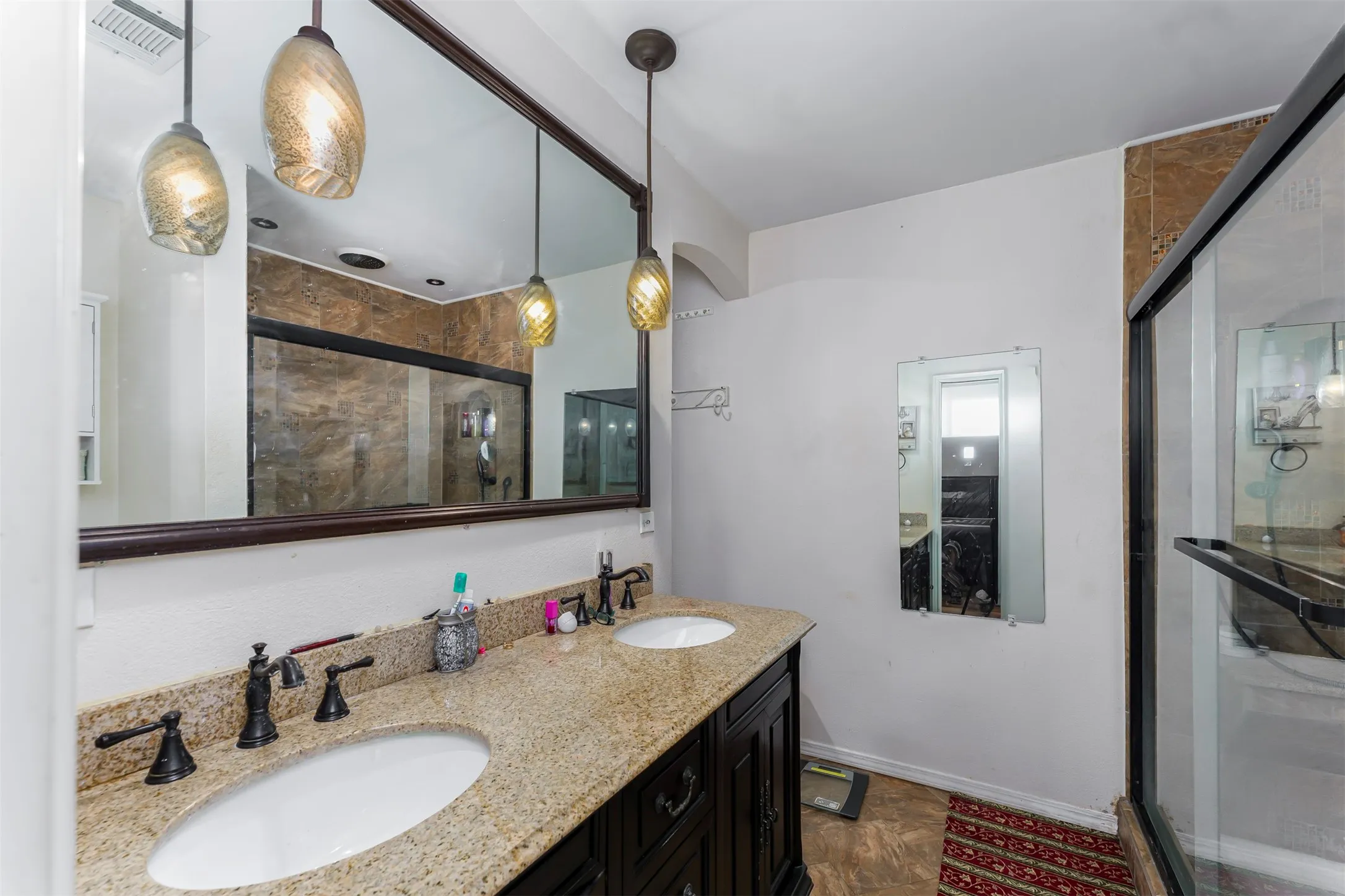 Dual sink vanity with a light speckled countertop, dark wood-finish cabinetry, and oil-rubbed bronze fixtures