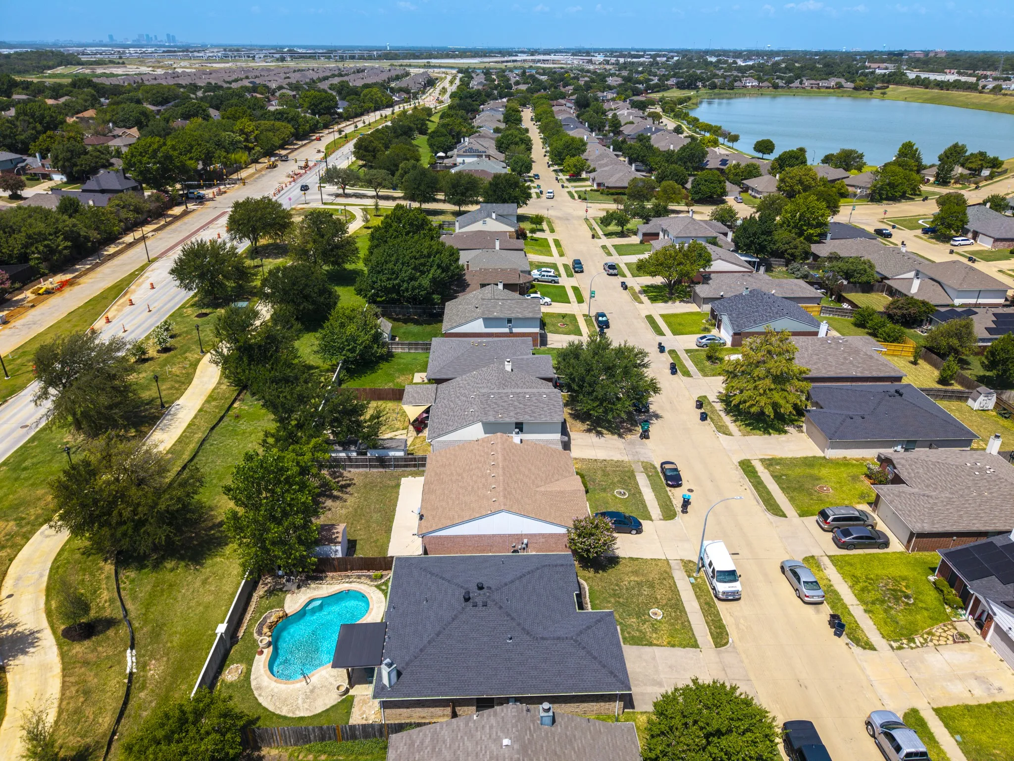 Residential neighborhood featuring a curvilinear swimming pool with integrated spa, paved patio, and mature landscaping