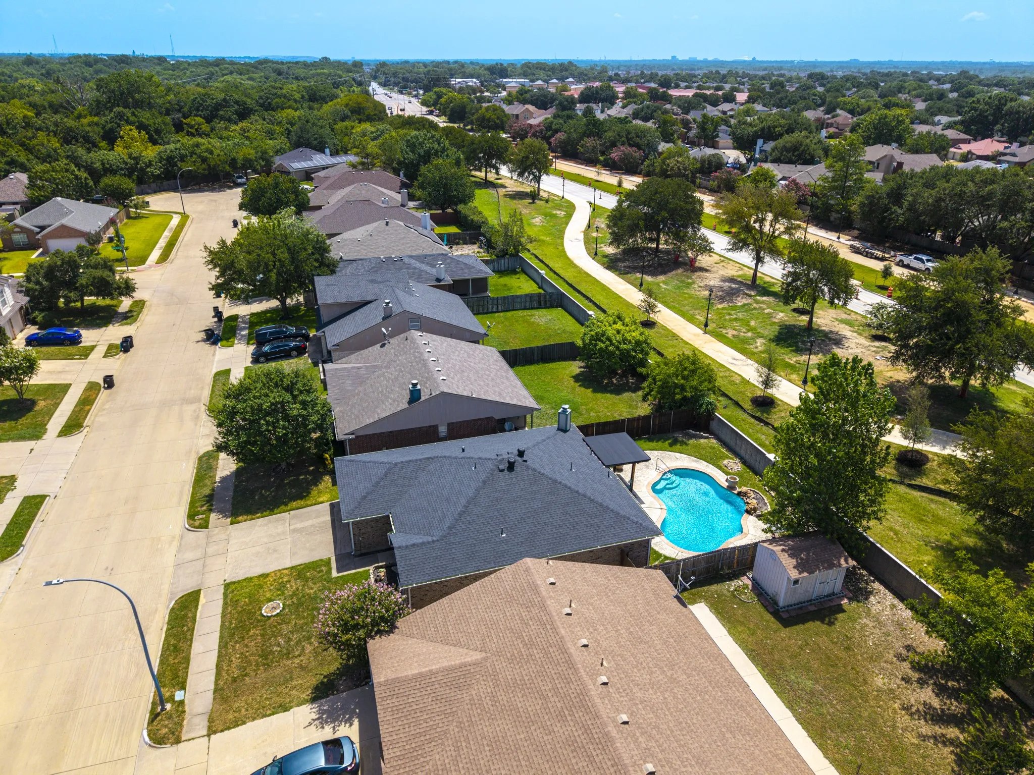 Backyard featuring a freeform swimming pool, concrete patio area, and a storage shed