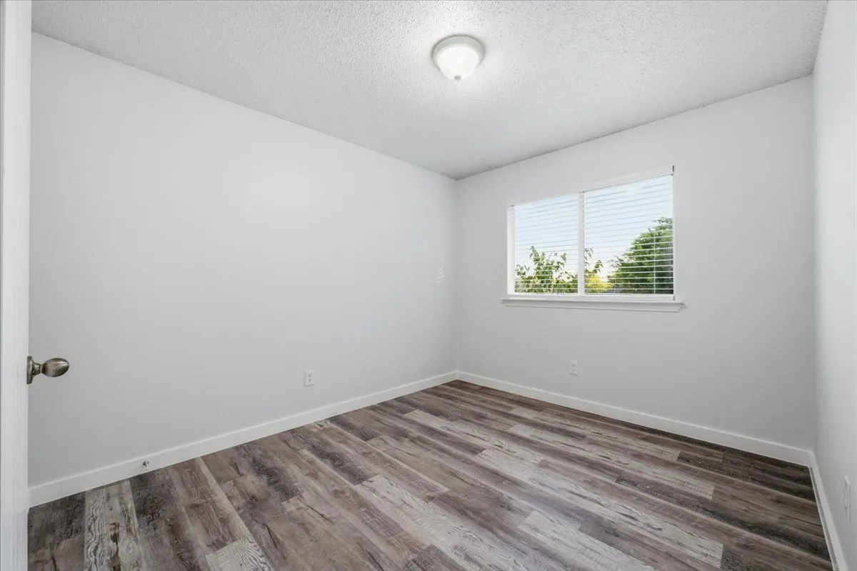 Room featuring wood-finish flooring, a window with blinds, and a ceiling-mounted light fixture