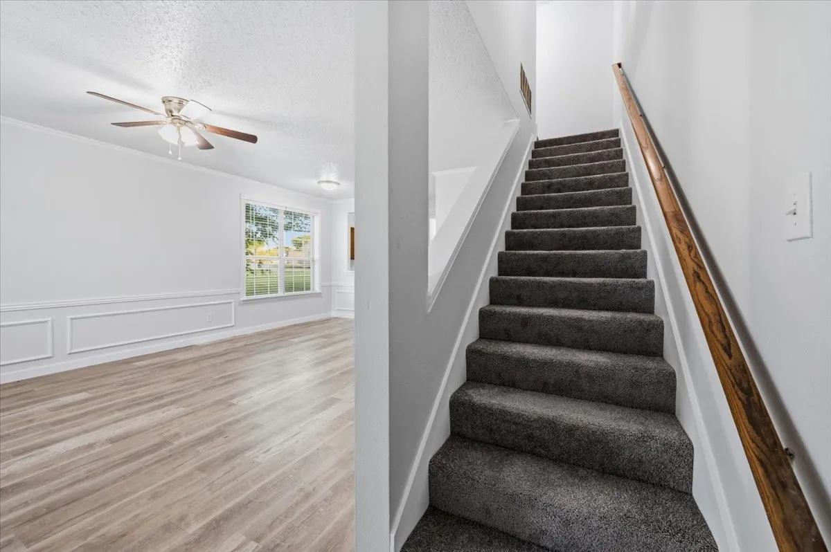 Staircase with gray carpeted treads and a wooden handrail