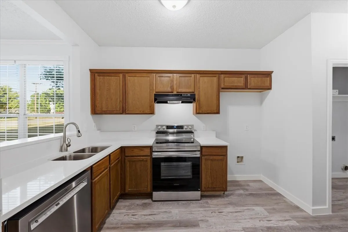 Kitchen featuring wood cabinetry, stainless steel appliances, white countertops, and wood-finish flooring