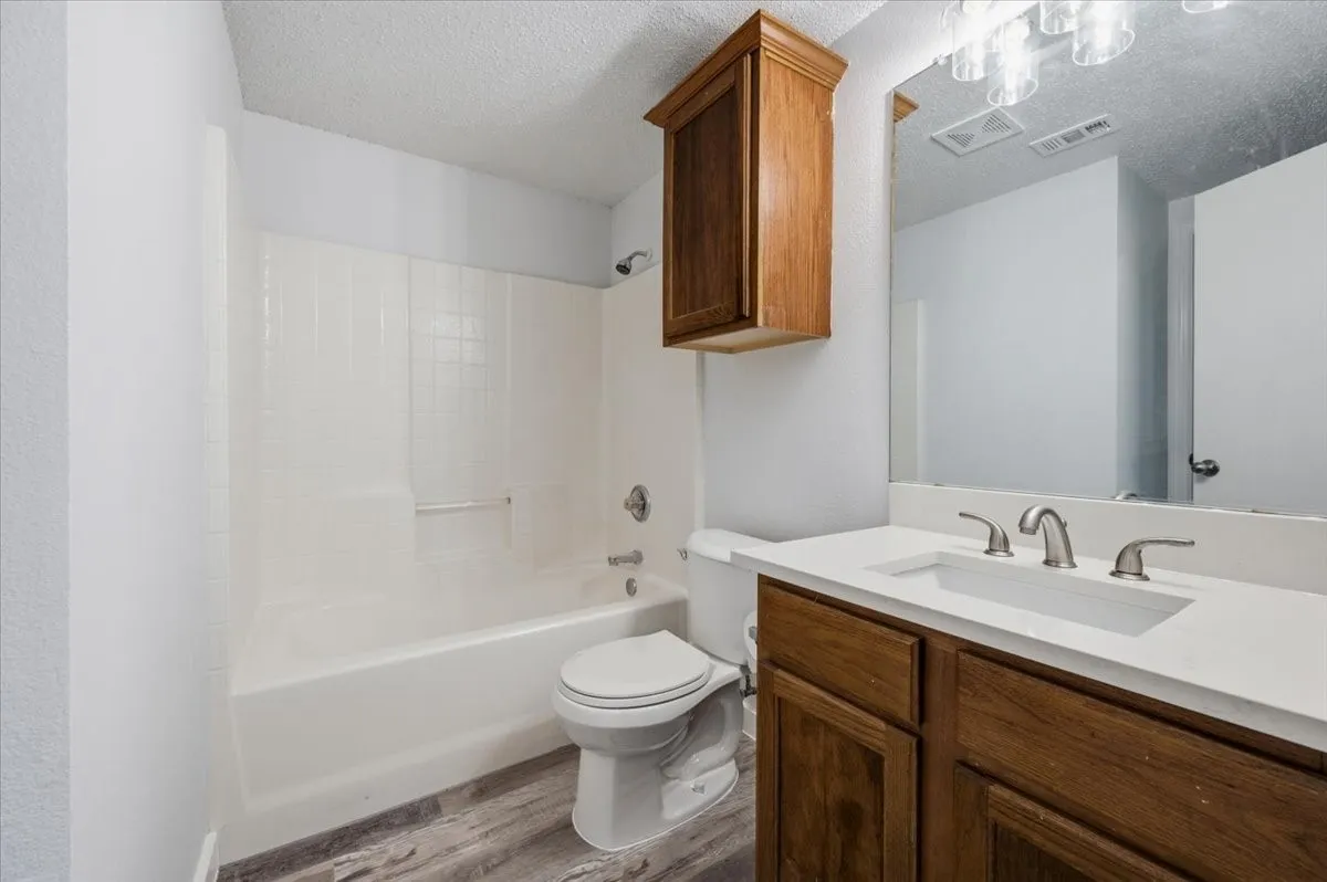 Bathroom featuring a single vanity with a white countertop, undermount sink, and wood-finish cabinetry