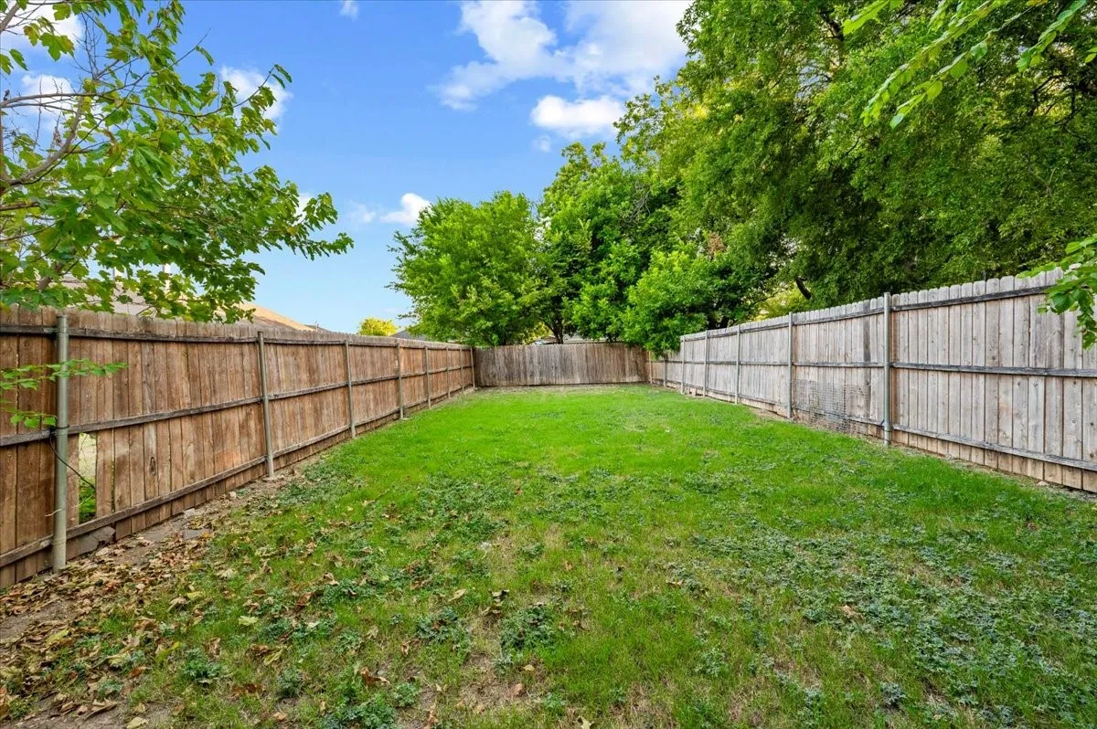 Spacious backyard featuring a grass lawn and wood-panel perimeter fencing