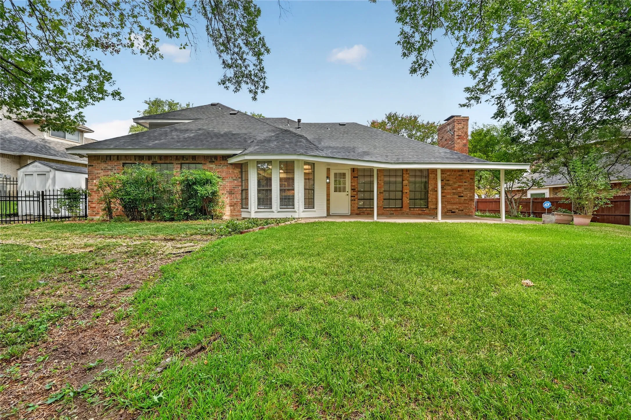 Expansive grassy yard area with a brick exterior home