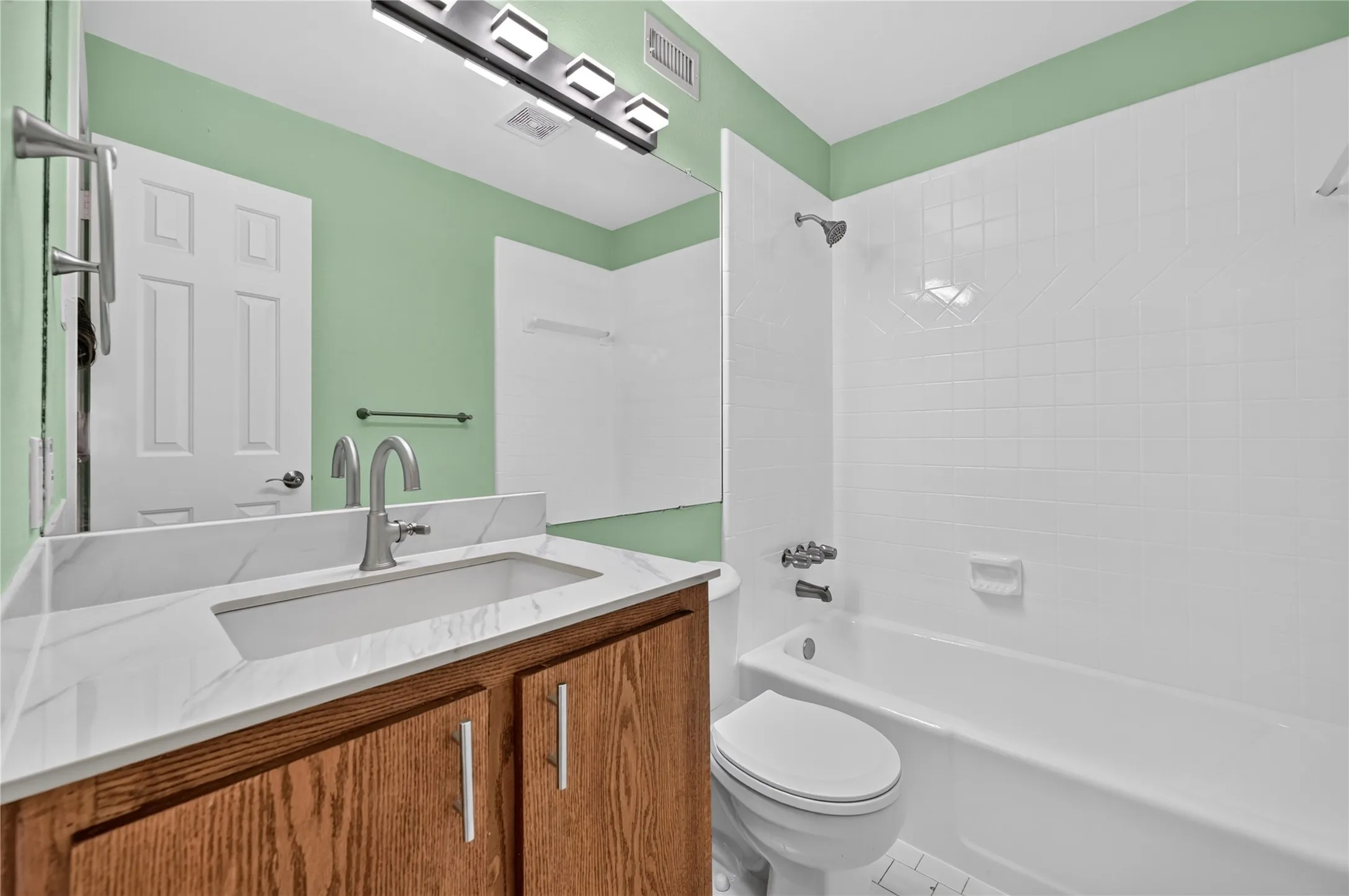 Bathroom vanity with a rectangular undermount sink, a stone-finish countertop, and a brushed nickel faucet