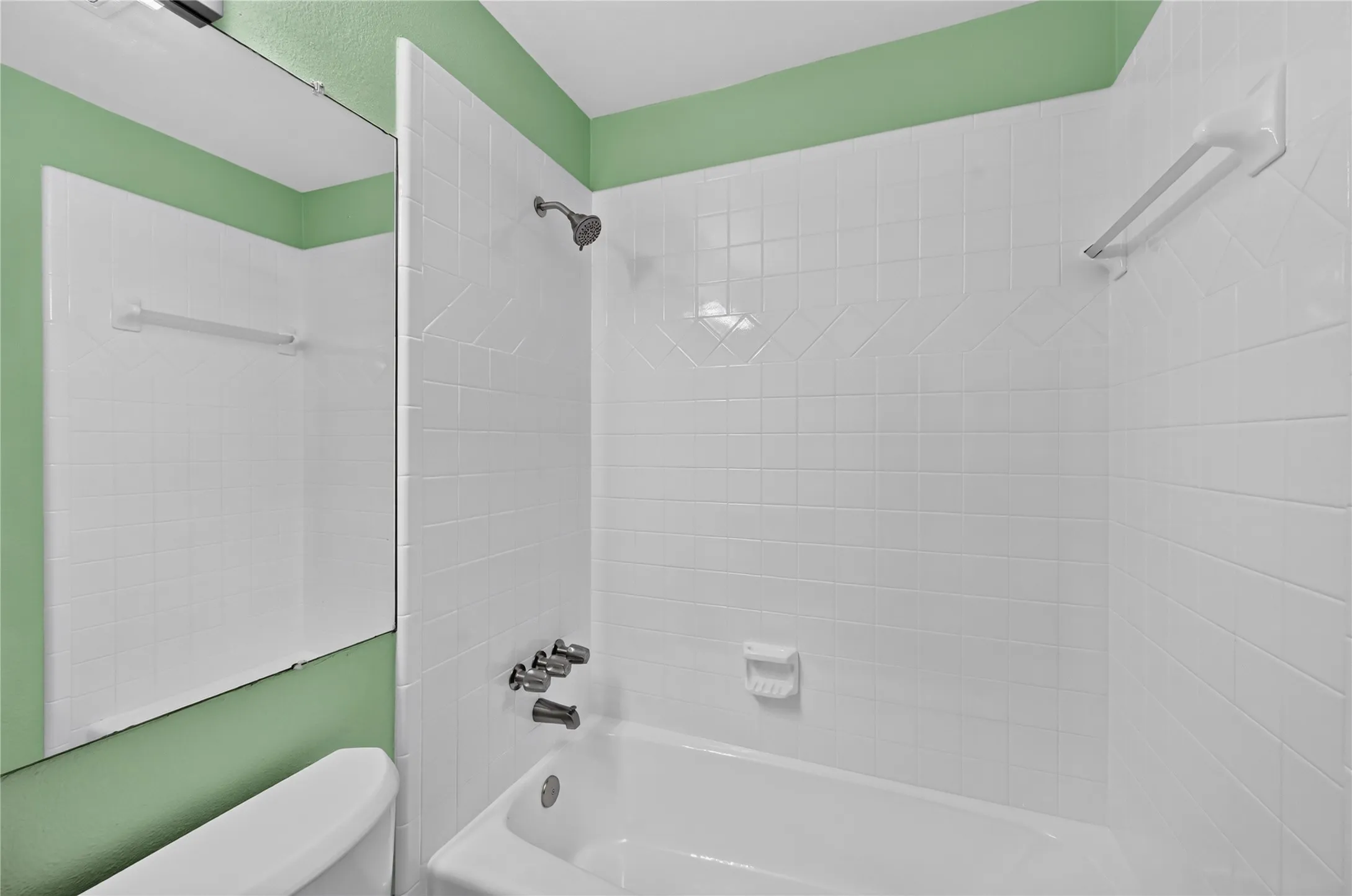 Full bathtub and shower combination with white tile surround