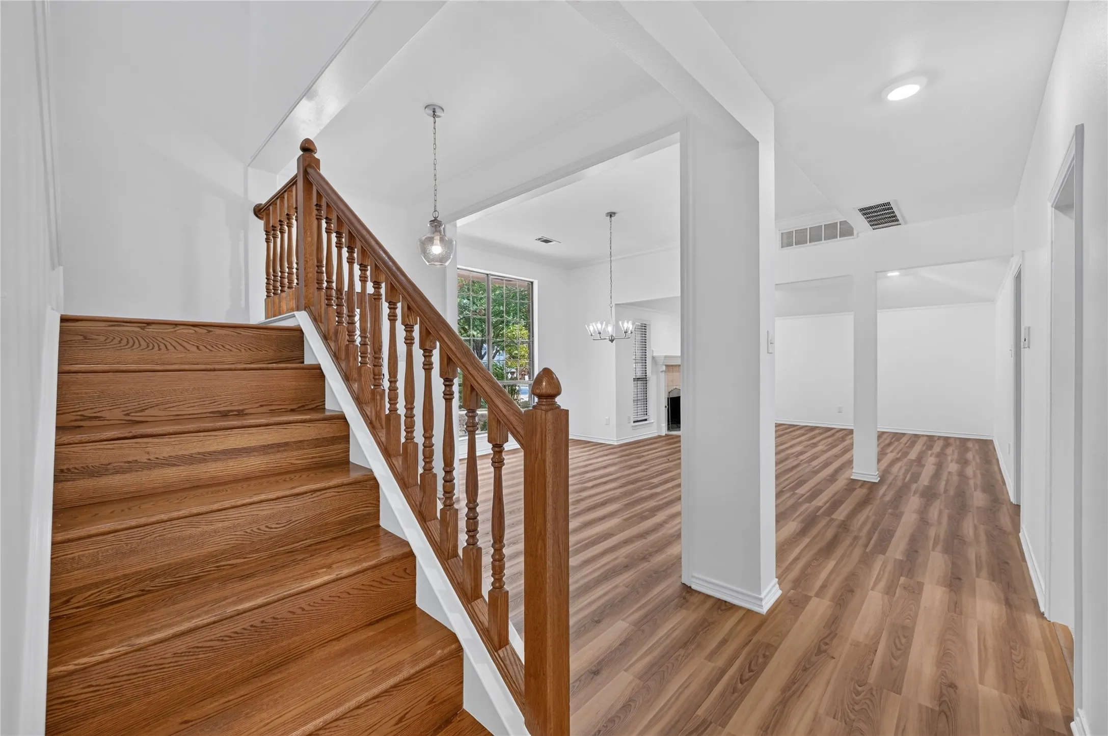 Hardwood staircase with turned balusters, wood-finish flooring, recessed lighting, and a modern chandelier
