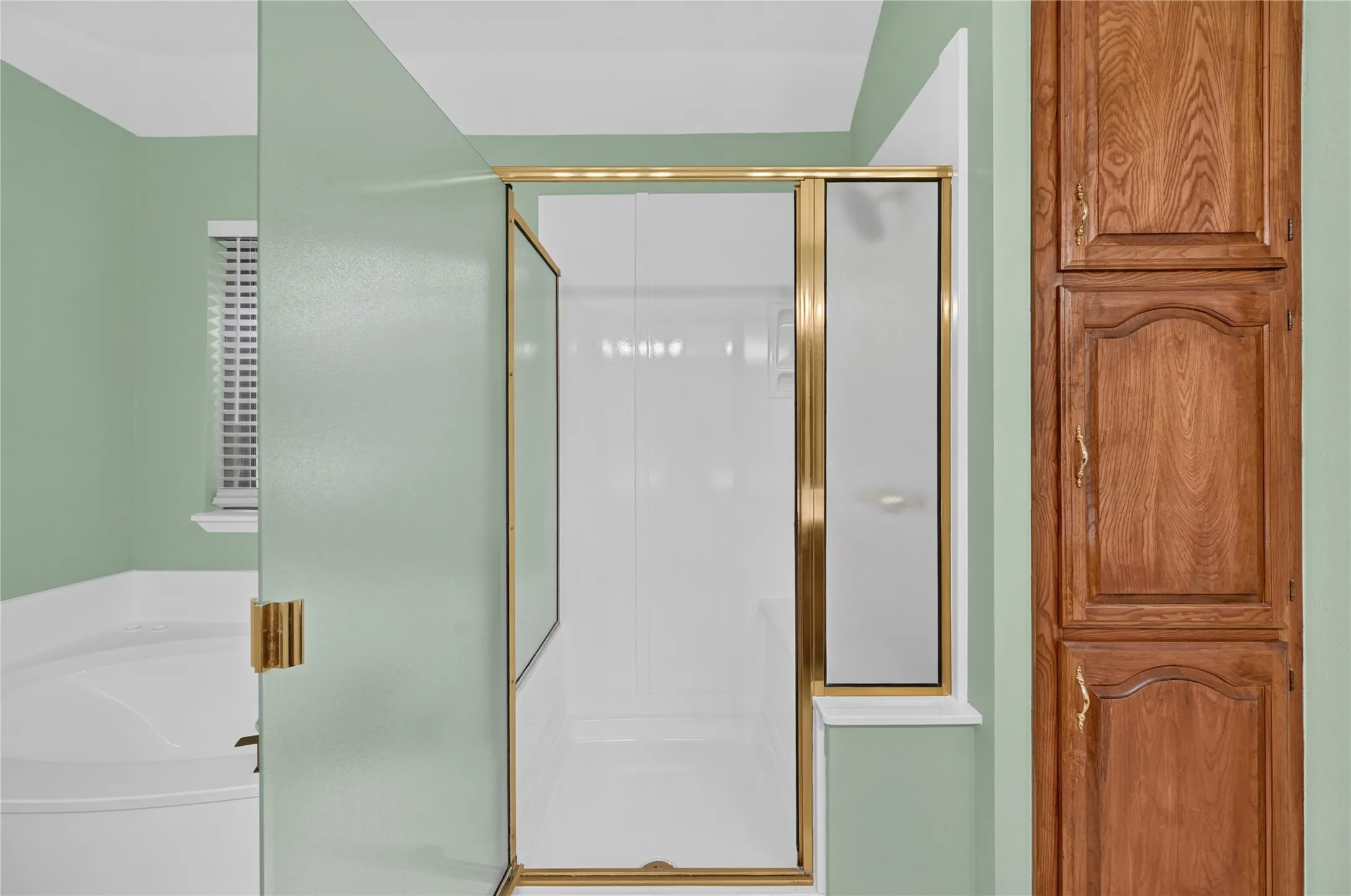 Shower enclosure with gold-tone framing, white base, and glass panels