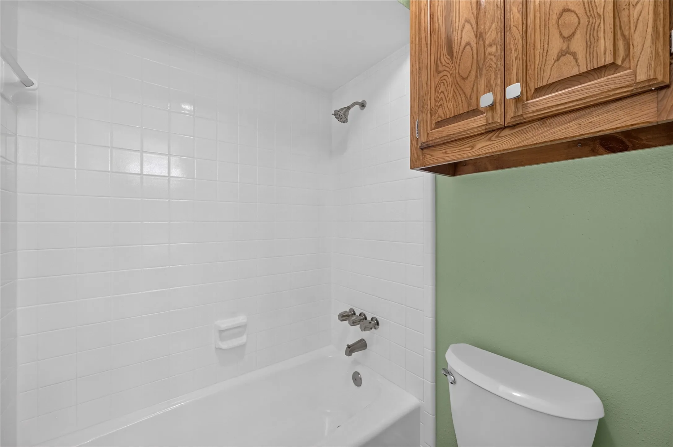 White tile shower surround with a white bathtub and chrome fixtures