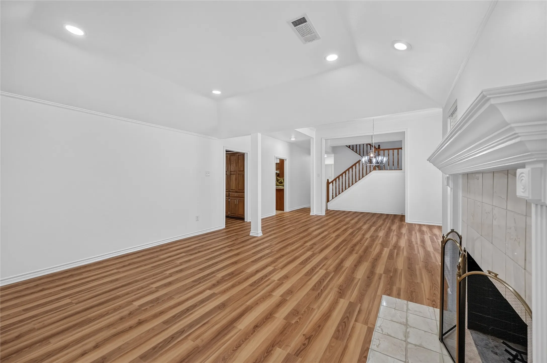 Bright interior space featuring wood-finish flooring and a white tile fireplace with an ornate mantel