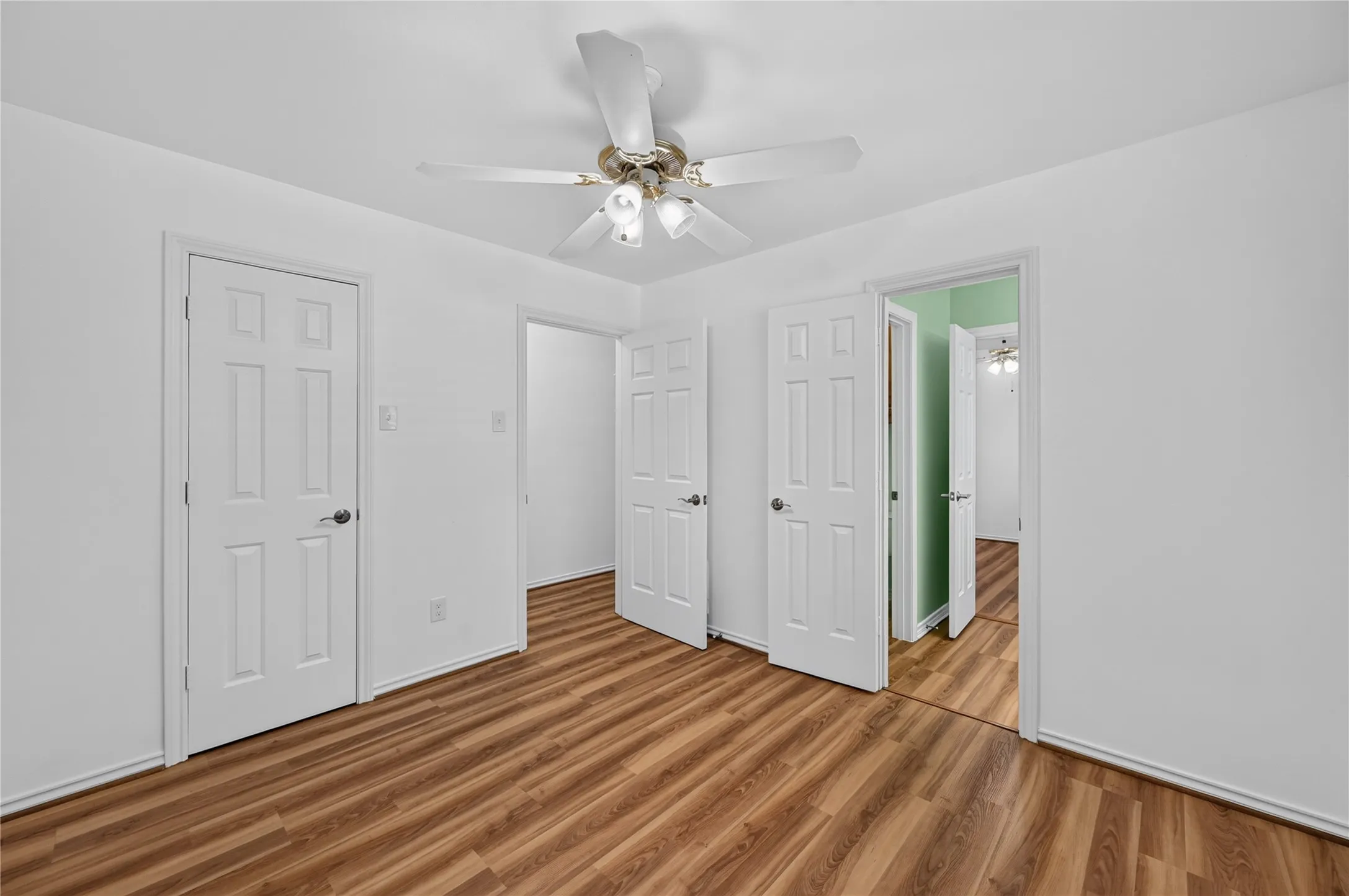 Room featuring wood-finish flooring, white walls, and a ceiling fan with integrated lighting