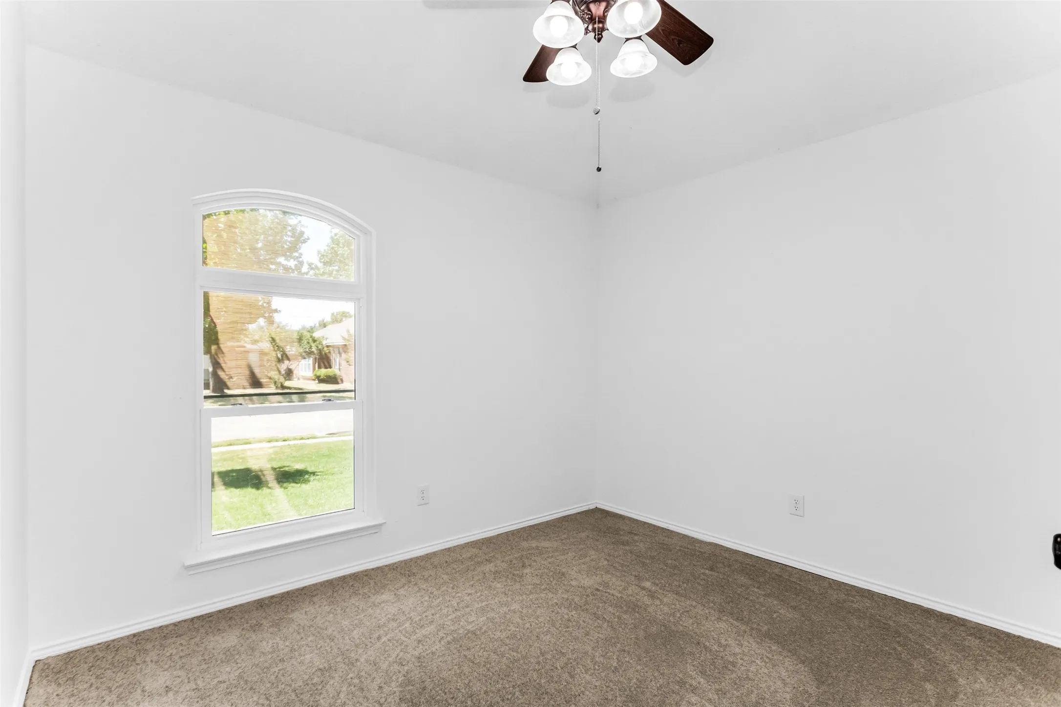 White painted walls, carpeted flooring, and an arched window